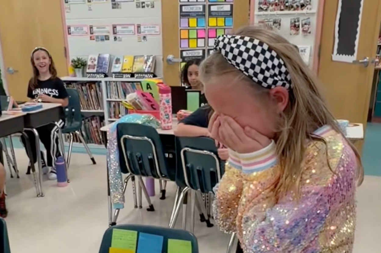 女の子が教室で驚きと感激の表情。机にはカラフルなメモが貼られている。