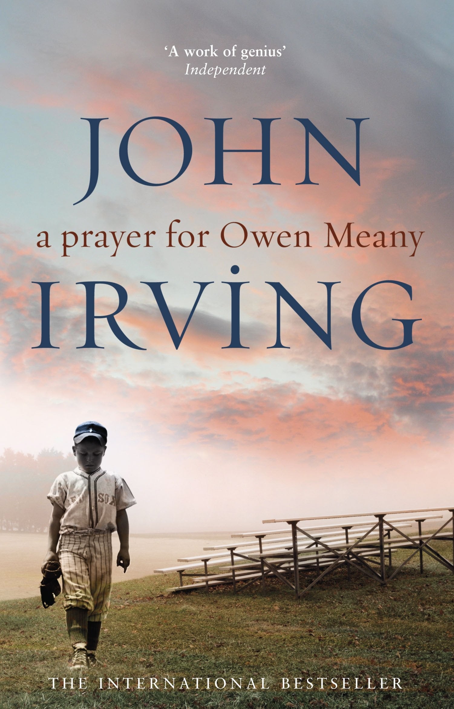 Book cover of "A Prayer for Owen Meany" by John Irving. Features a young boy in a baseball uniform, standing on a baseball field with empty bleachers