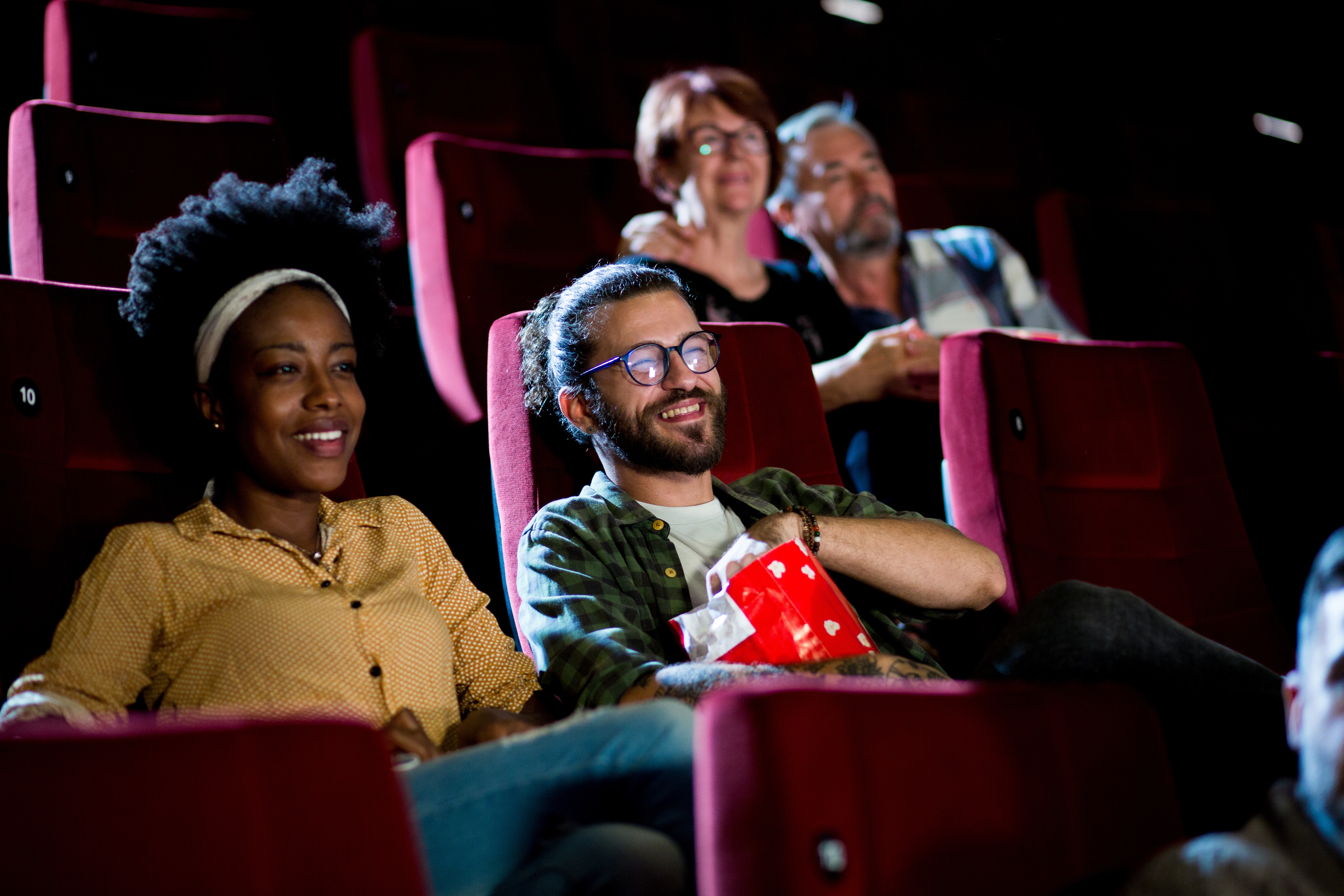 People sitting successful  a movie   theater, smiling and enjoying a film