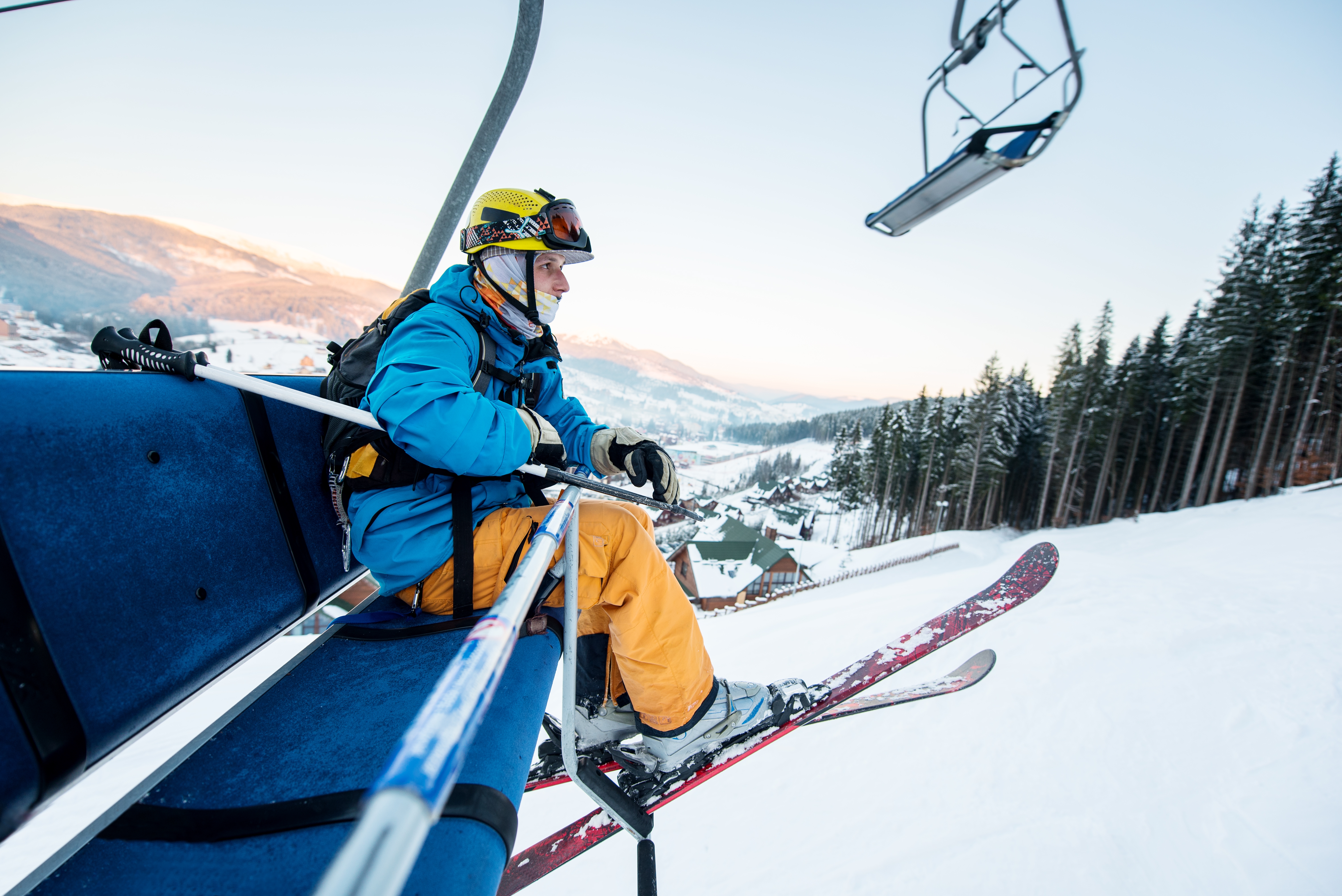 Person successful  skis  cogwheel  connected  a skis  lift, holding poles, overlooking a snowy upland  landscape, suggesting outdoor leisure and wintertime  tourism economy