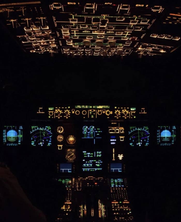 Illuminated cockpit of an craft  with galore   controls, screens, and gauges lit up, showing a opposition  against the acheronian  background