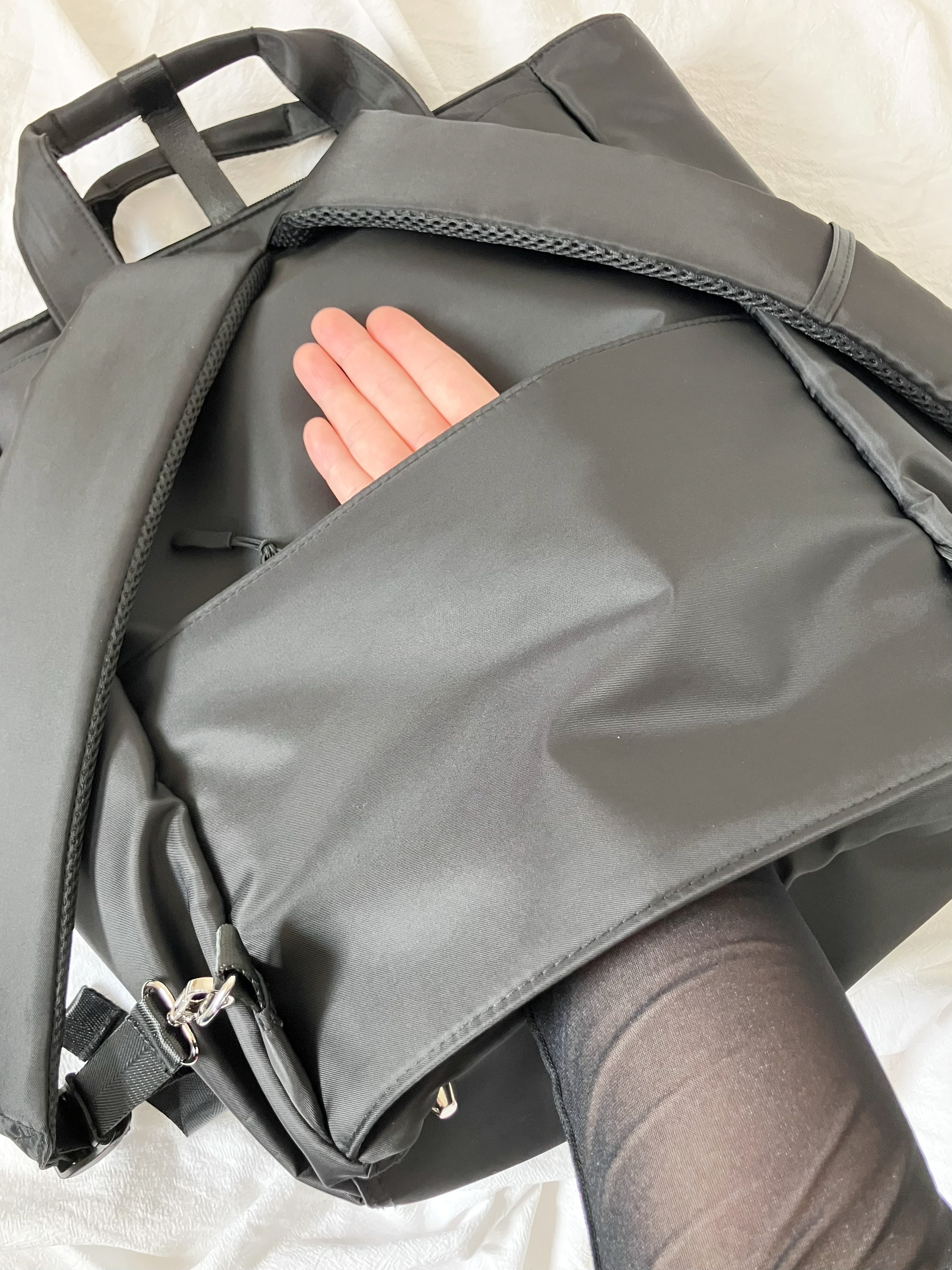 ワークマンの「しごできカバン 撥水防汚3WAYリュック」黒いバッグのファスナー開口部から片手が入っている様子。