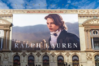 ラルフ・ローレンの広告掲示板が歴史的な建物に設置され、道沿いに車と歩行者が見られる。