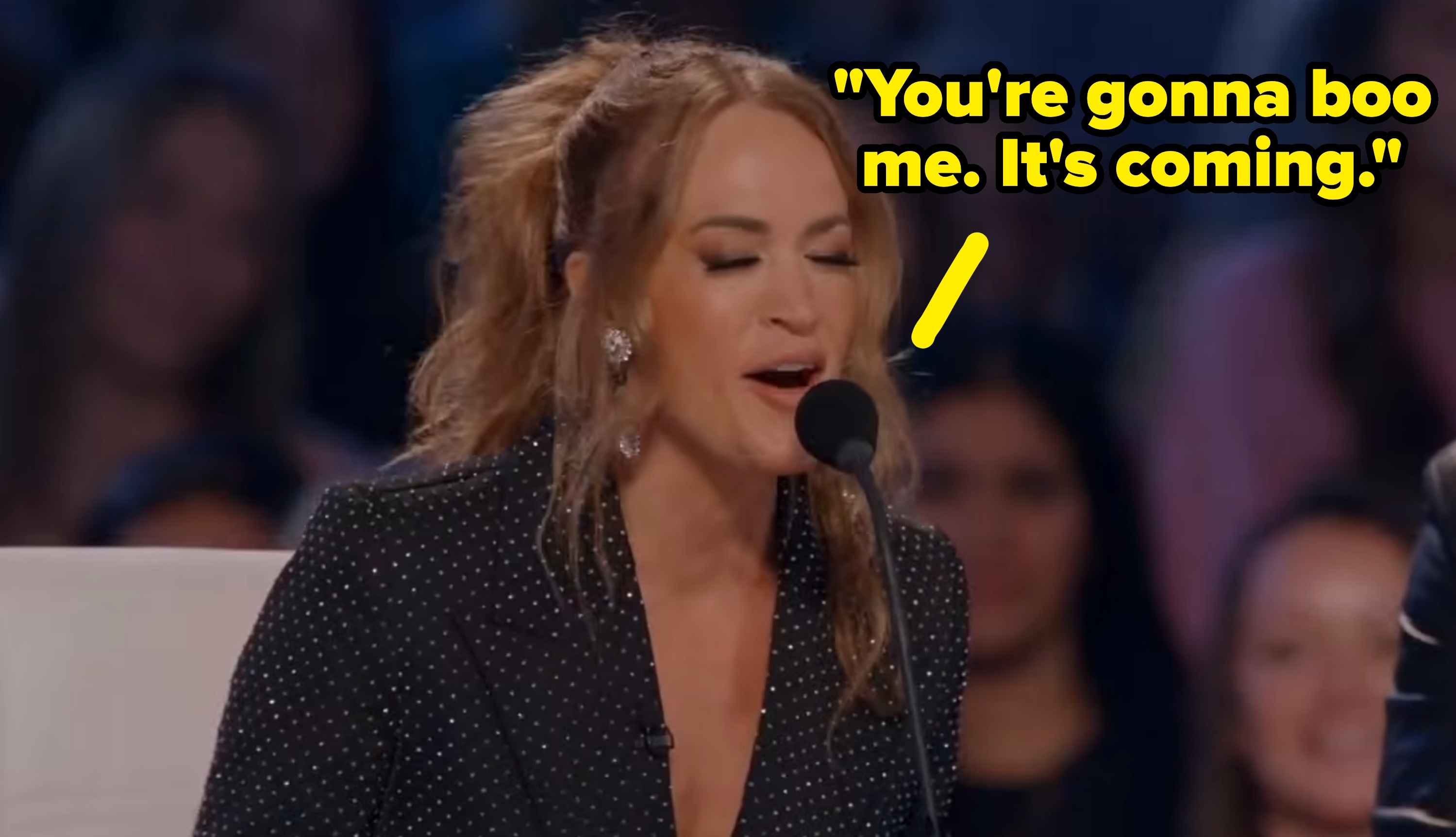 Carrie Underwood wearing a stylish polka-dot outfit speaks into a microphone astatine a nationalist event