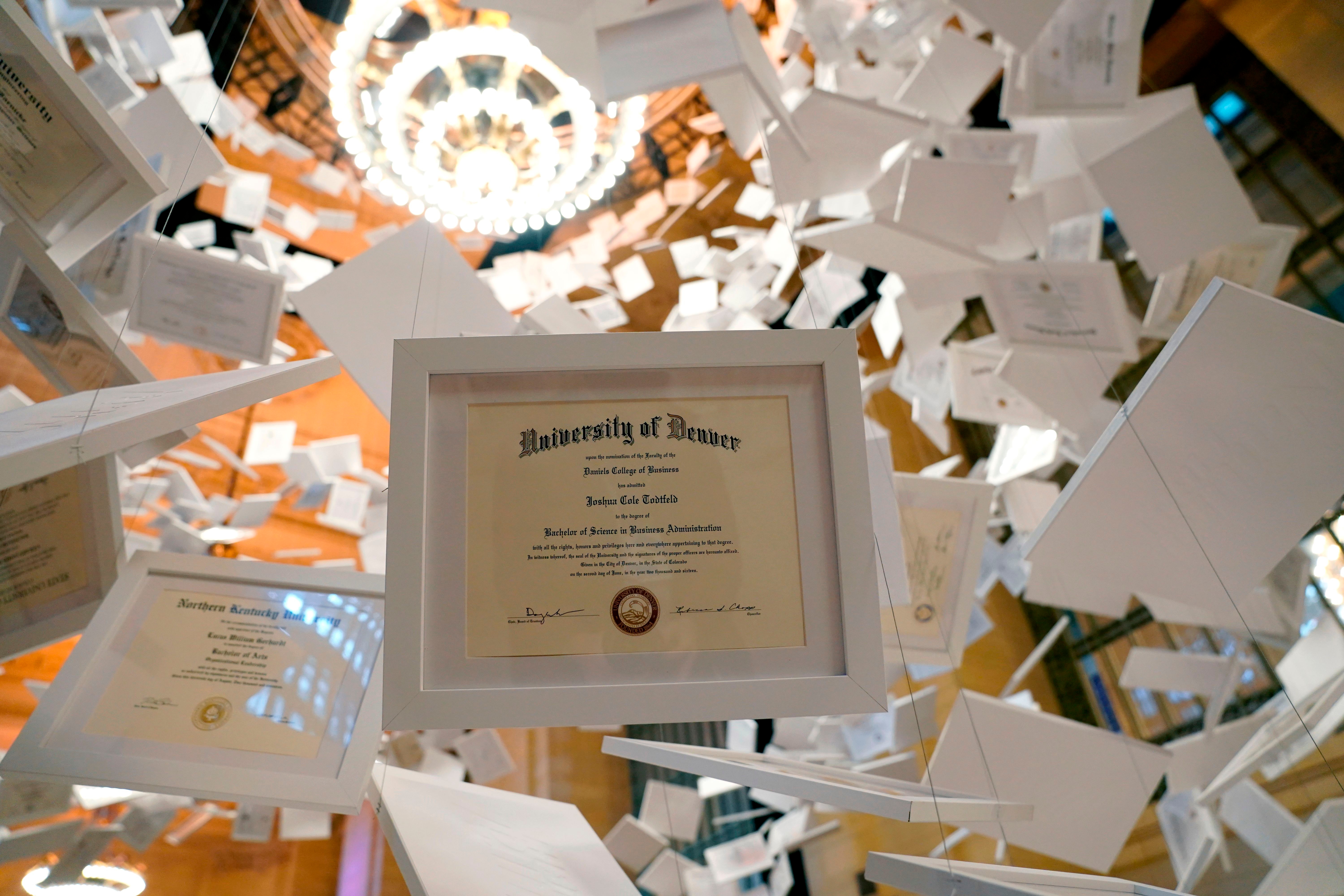Framed assemblage   diplomas are suspended successful  the air, appearing to interval  successful  a melodramatic  architectural setting
