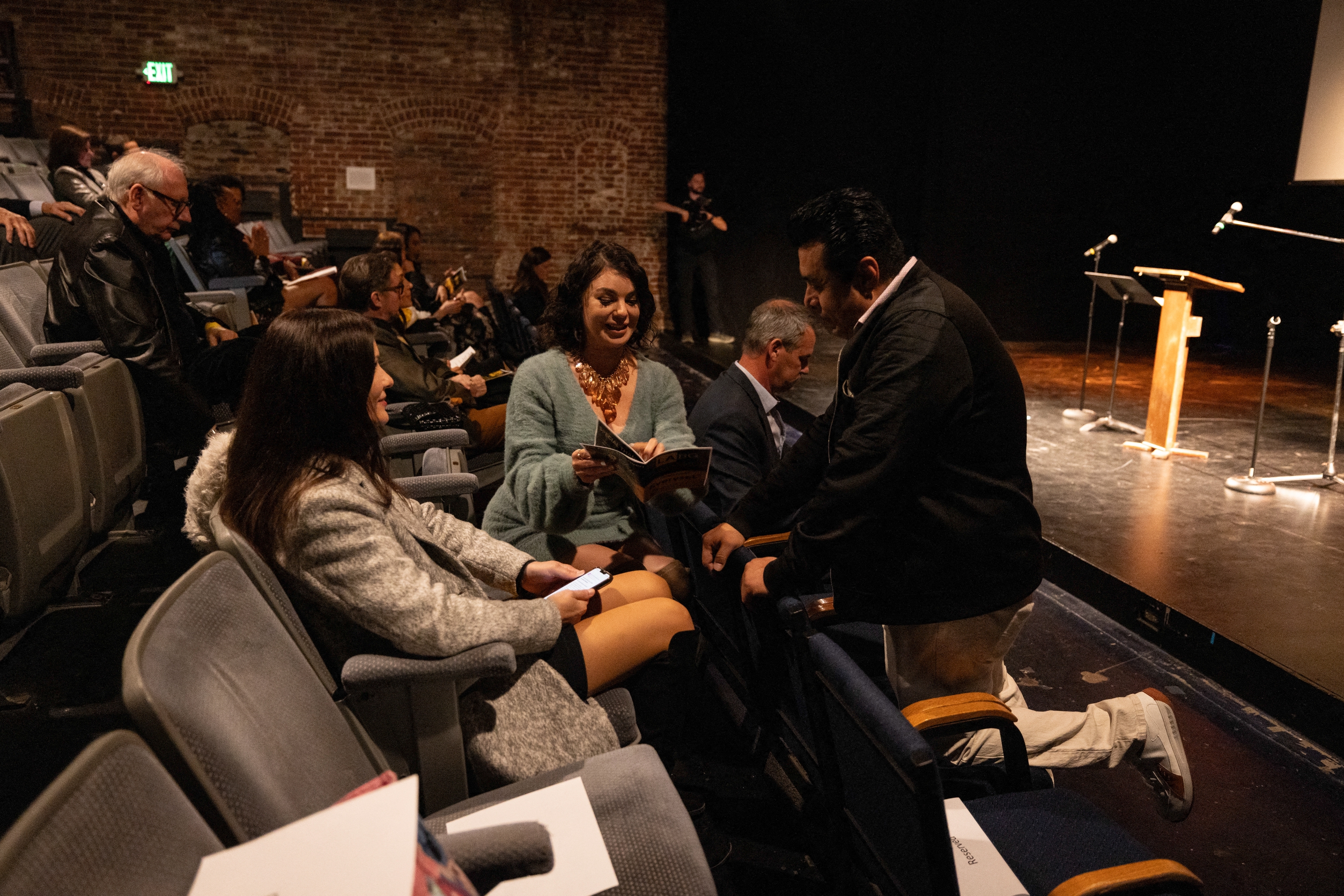 Audience interacting earlier  a speaking event, with radical   seated and conversing successful  a theatre  setting. A podium is disposable   connected  stage