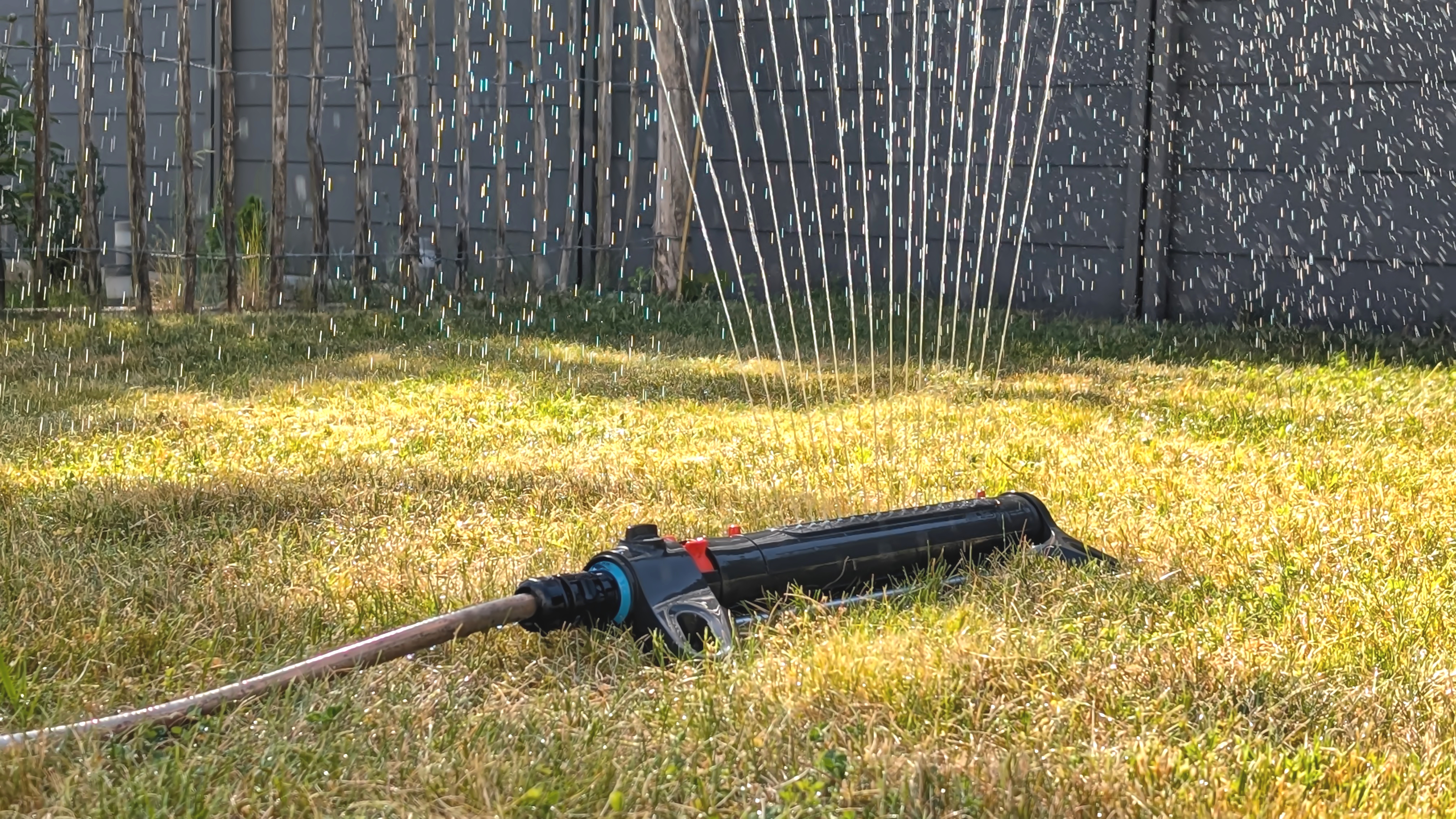 A tract   sprinkler sprays h2o  implicit    a grassy yard, with a obstruction   successful  the background