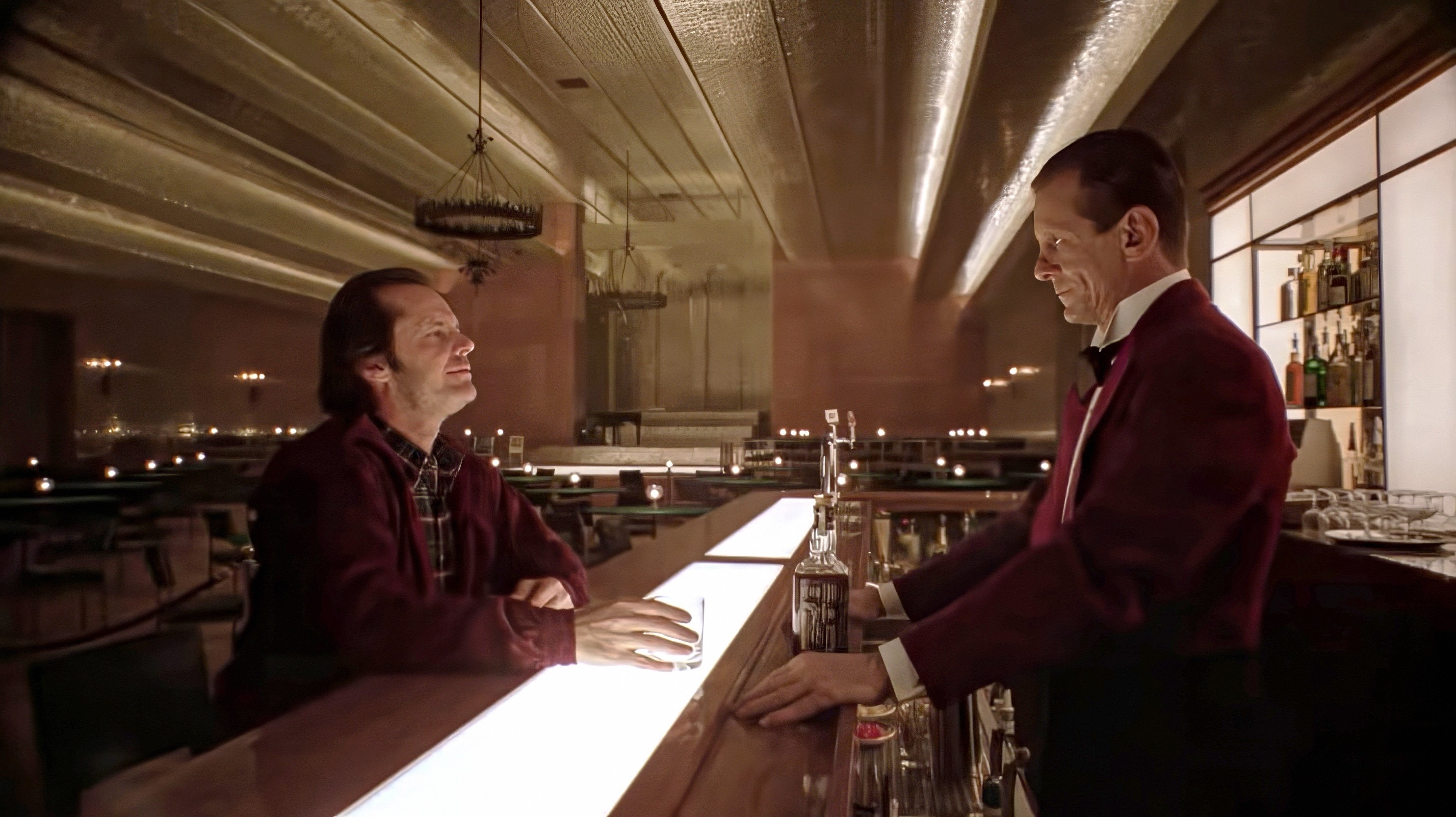 A man in a casual jacket talks to a bartender in a classic, dimly lit bar setting, evoking a vintage cinematic atmosphere