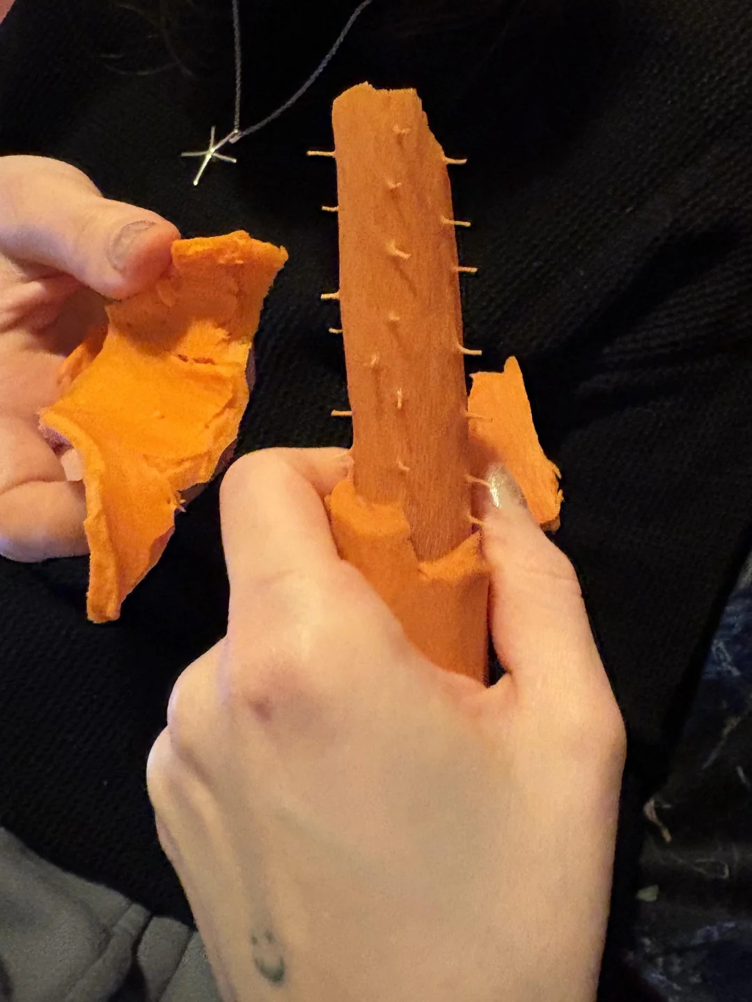 Person peeling clay from a cactus-shaped entity  with tiny  spikes portion    holding it successful  their hands