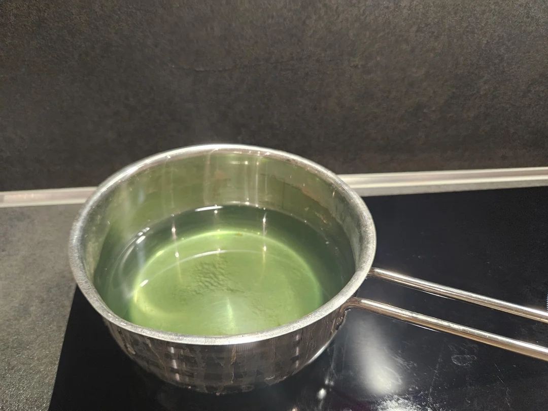 A saucepan with greenish  liquid connected  an electrical  stove