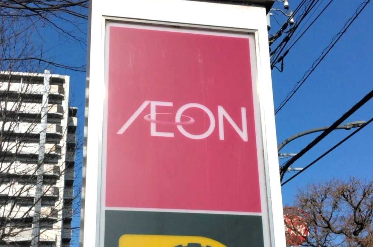 AEONの看板と駐車場サインが写っている。背景にビルと電線が見える。