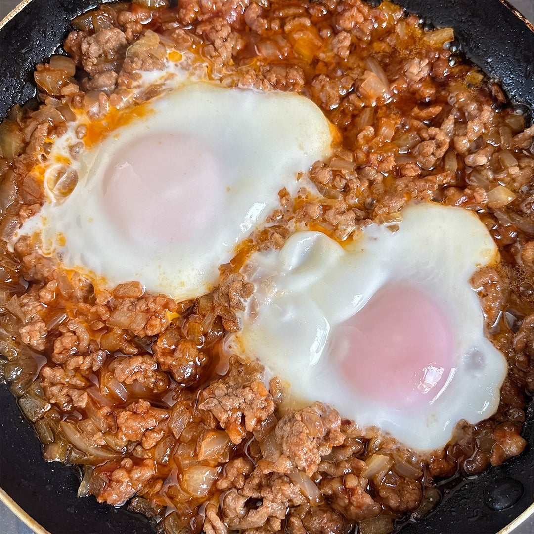 ひき肉と玉ねぎの煮込みに、目玉焼きが2つのった料理。