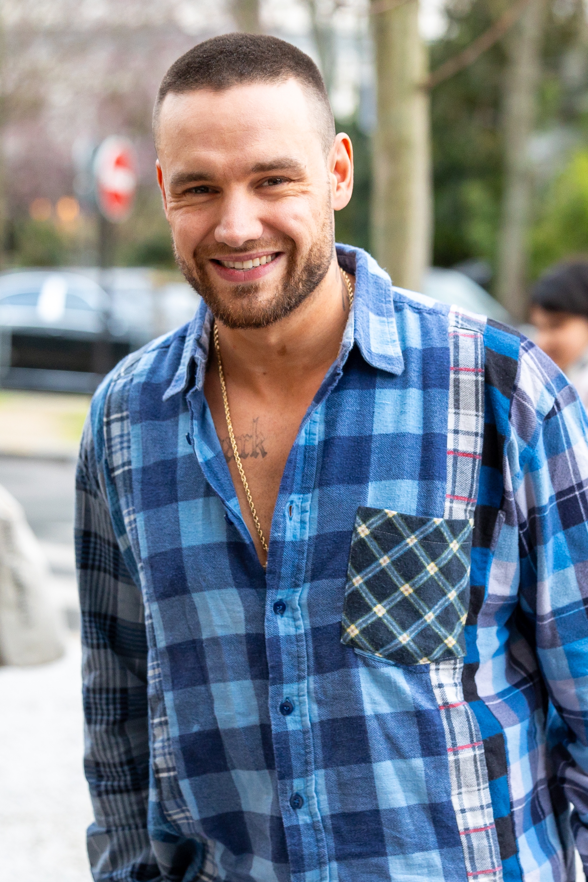 Person successful  a plaid garment  smiling outdoors, wearing a necklace