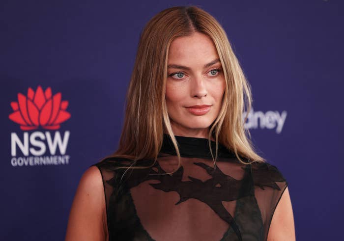 Person successful  a sleeveless, semi-transparent achromatic  formal  with floral plan  astatine  a ceremonial  event