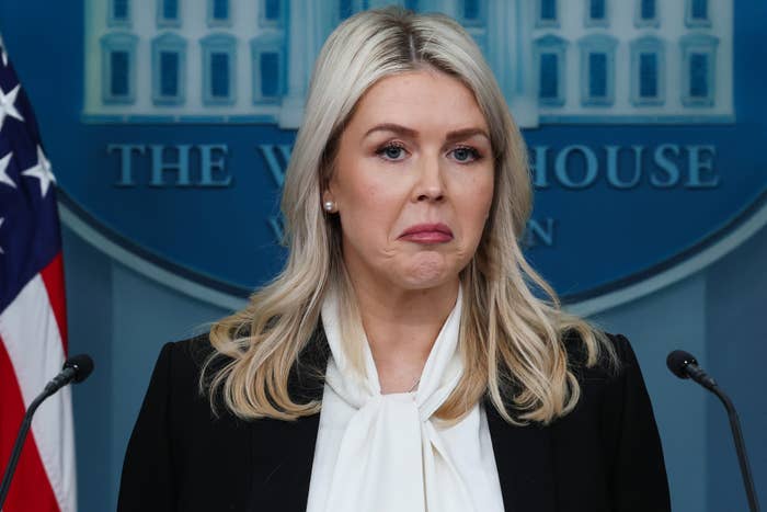 A idiosyncratic   astatine  a podium successful  beforehand   of a White House backdrop, wearing a achromatic  blazer and achromatic  blouse, with a thoughtful expression