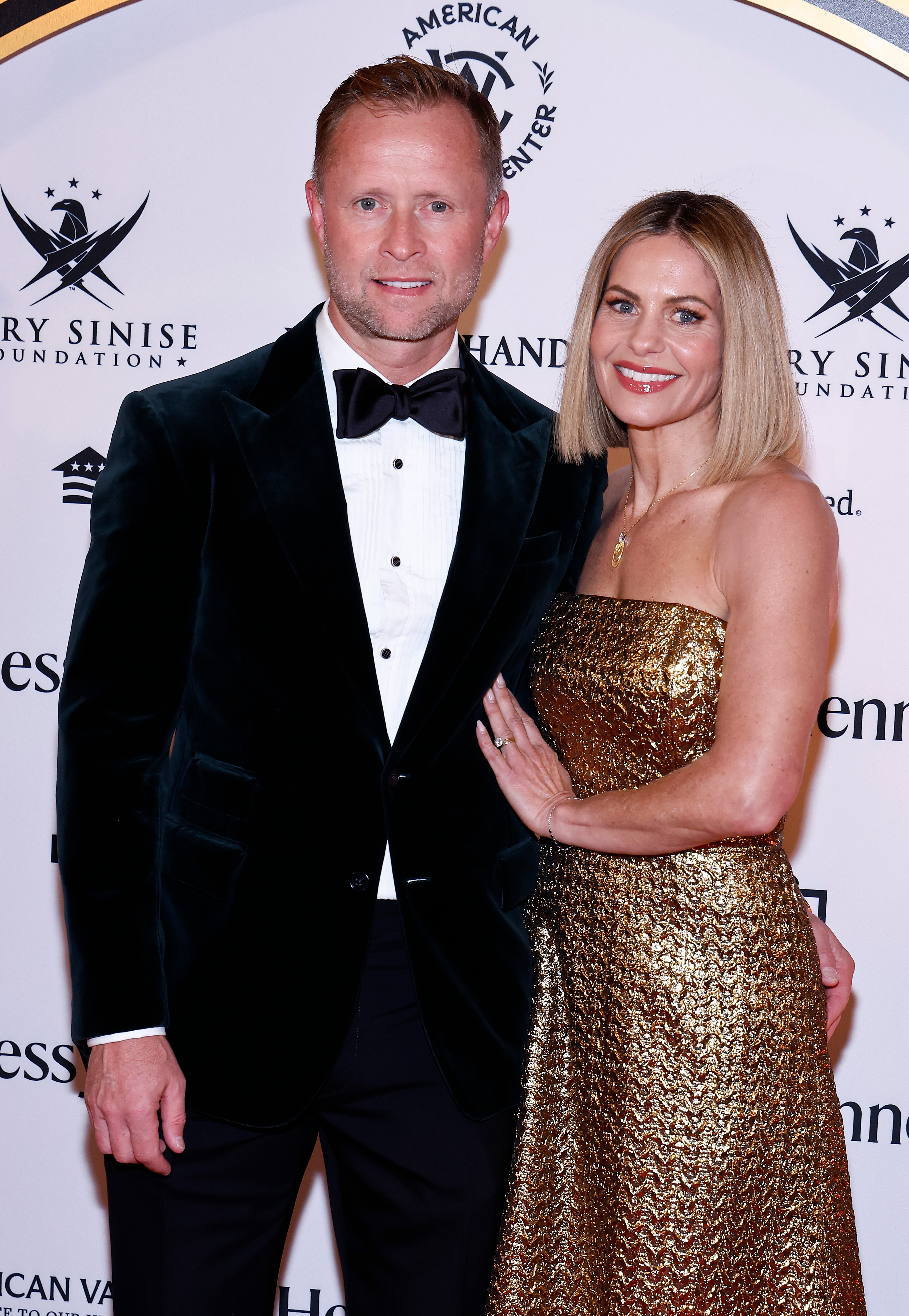 A antheral   successful  a tuxedo and a pistillate   successful  a strapless, golden  gown airs  unneurotic  connected  a reddish  carpet astatine  an event. 