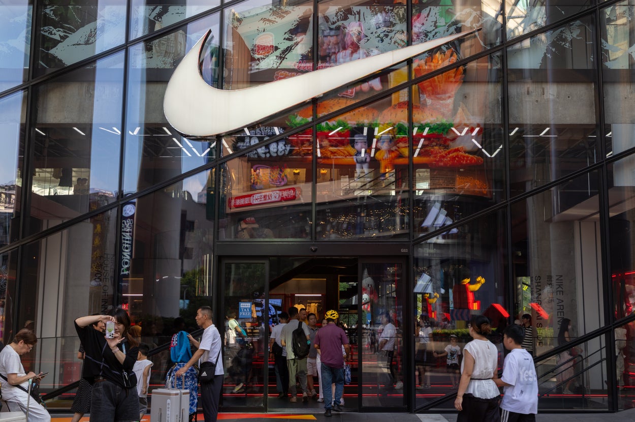 人々が行き交う賑やかなナイキストアの前景。ガラスに店舗内のディスプレイが反射している。