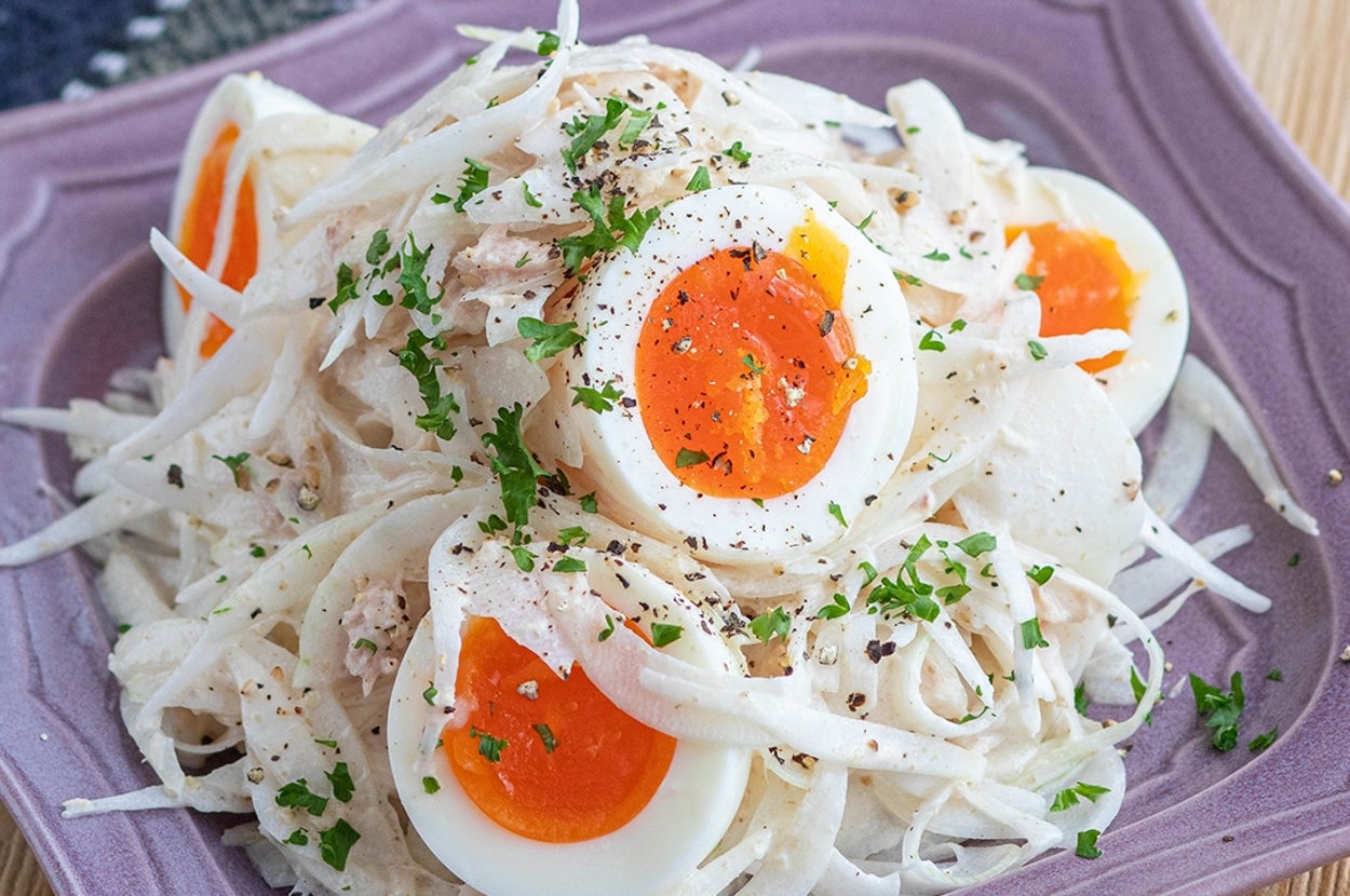 ゆで卵とスライスオニオンのサラダが皿に盛られている。パセリが散らされ、黒胡椒が振られている。