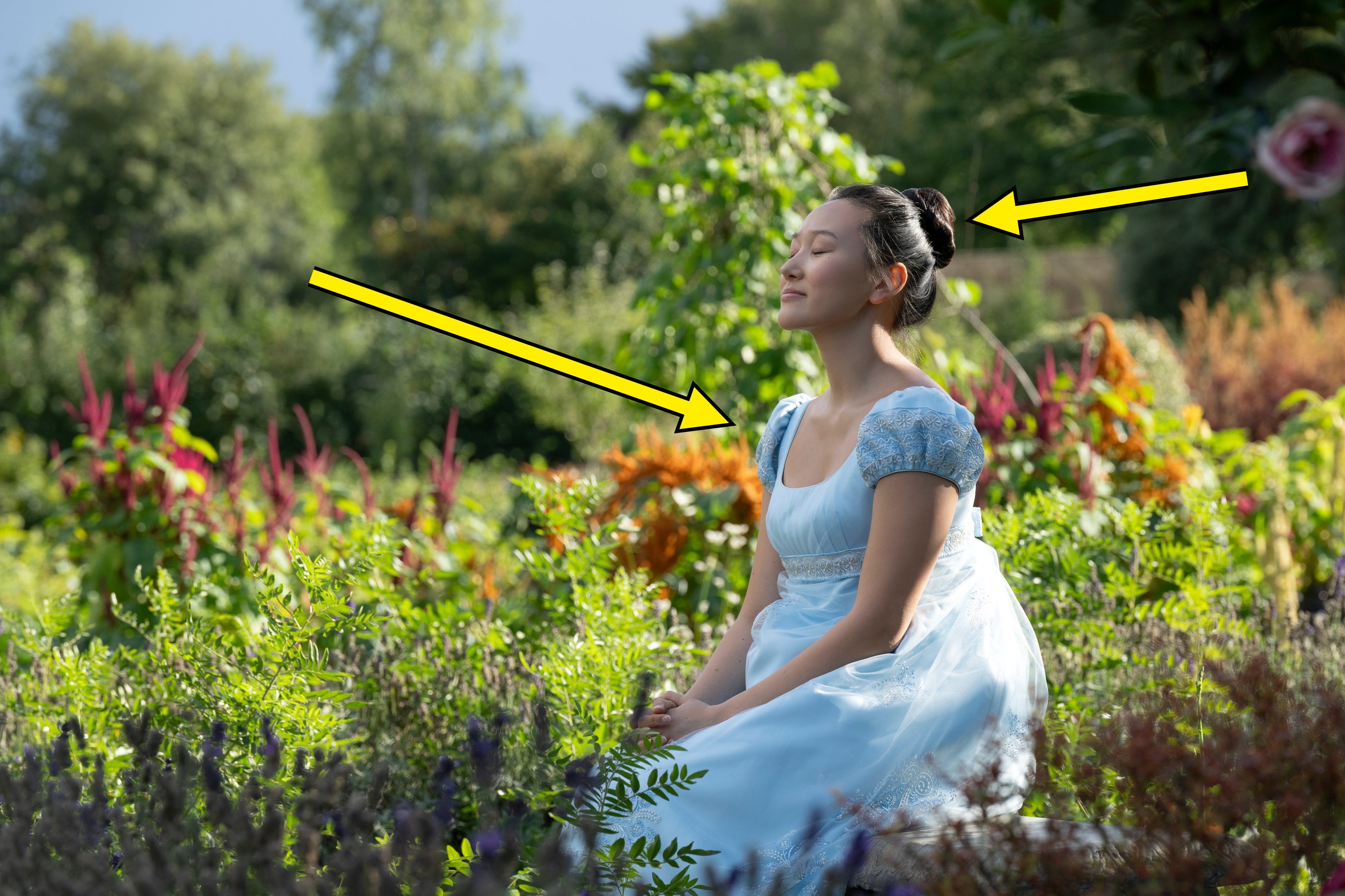 Person in period-style dress sits peacefully in a lush garden, eyes closed, suggesting tranquility or reflection