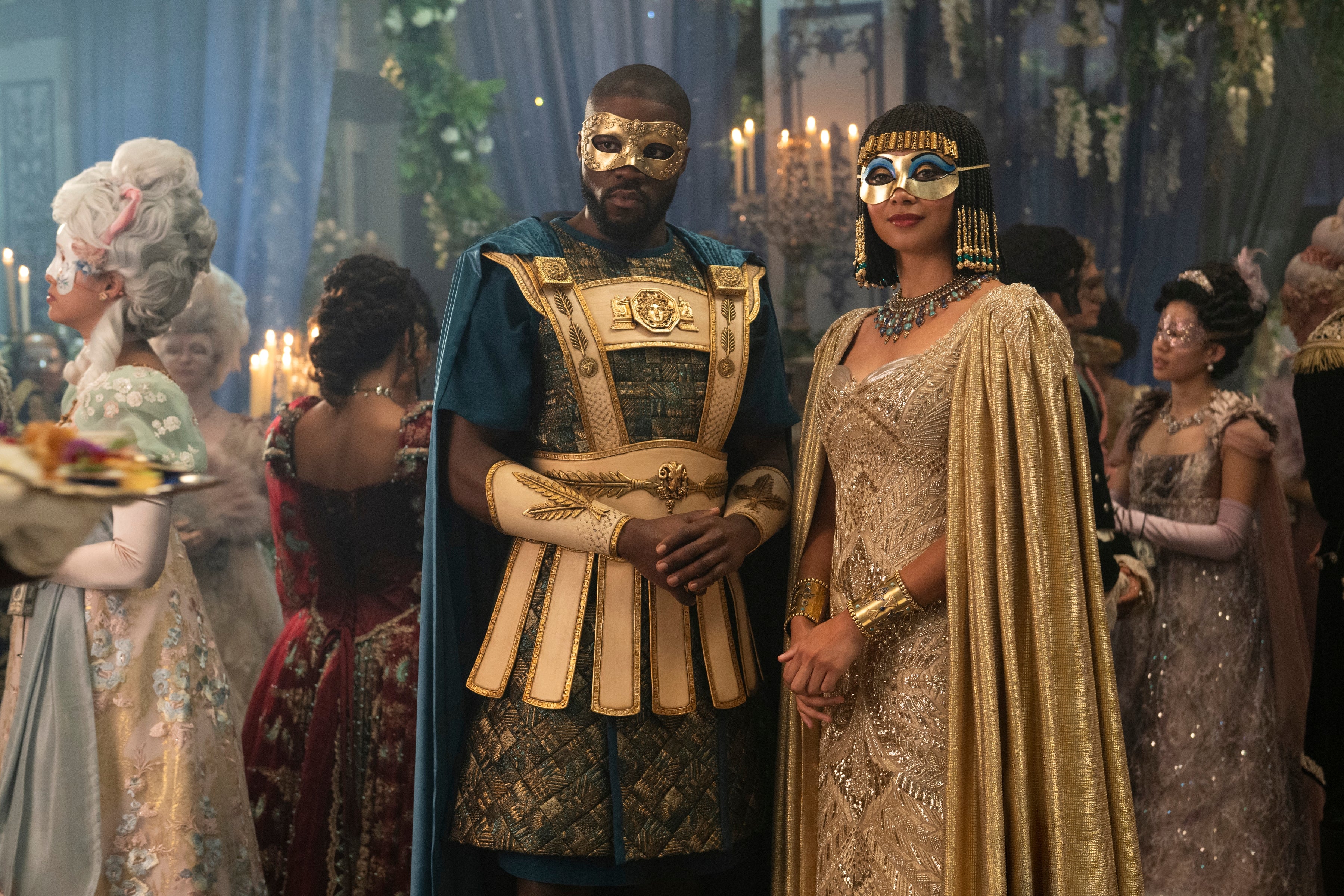 People in ornate costumes and masks at a lavish party or ball, possibly from a historical or fantasy film or TV series