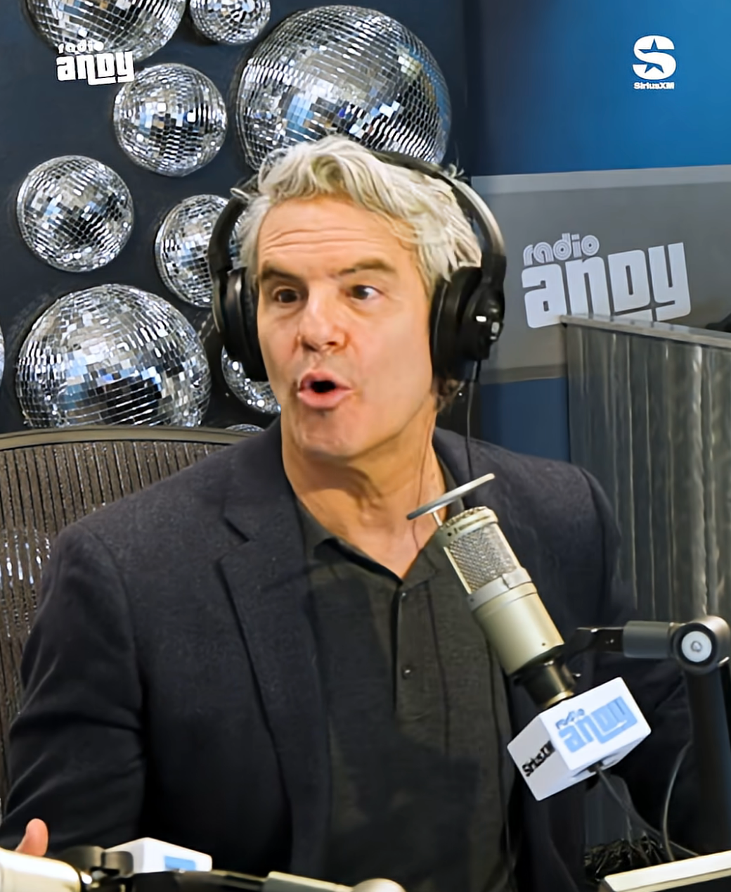 Man successful  a vigor   workplace  wearing headphones and speaking into a microphone. Multiple disco balls decorate the background