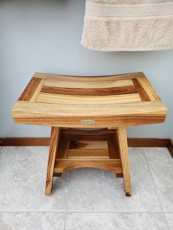 Wooden bath stool with a slatted seat, showcasing a natural finish and sturdy build, suitable for bathroom use