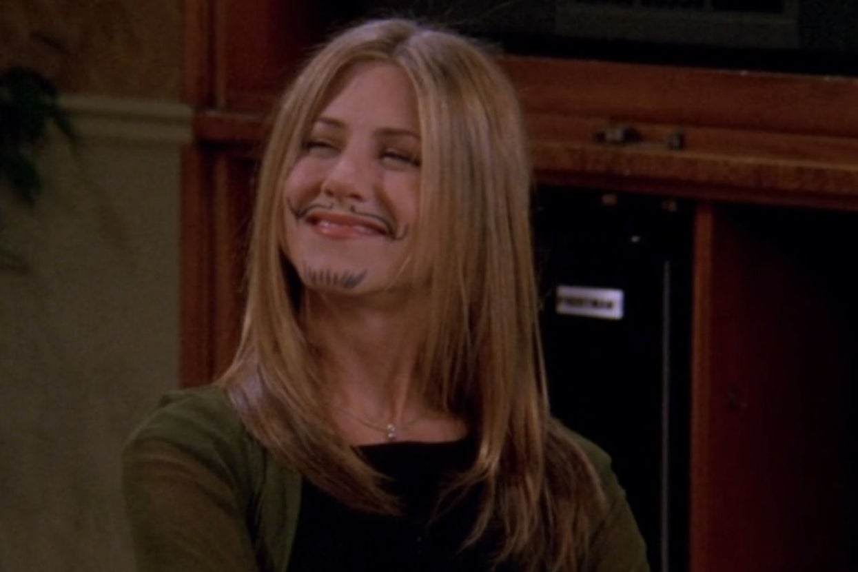 Person with a playful smile has a drawn-on mustache and beard, resembling a humorous moment from a TV show