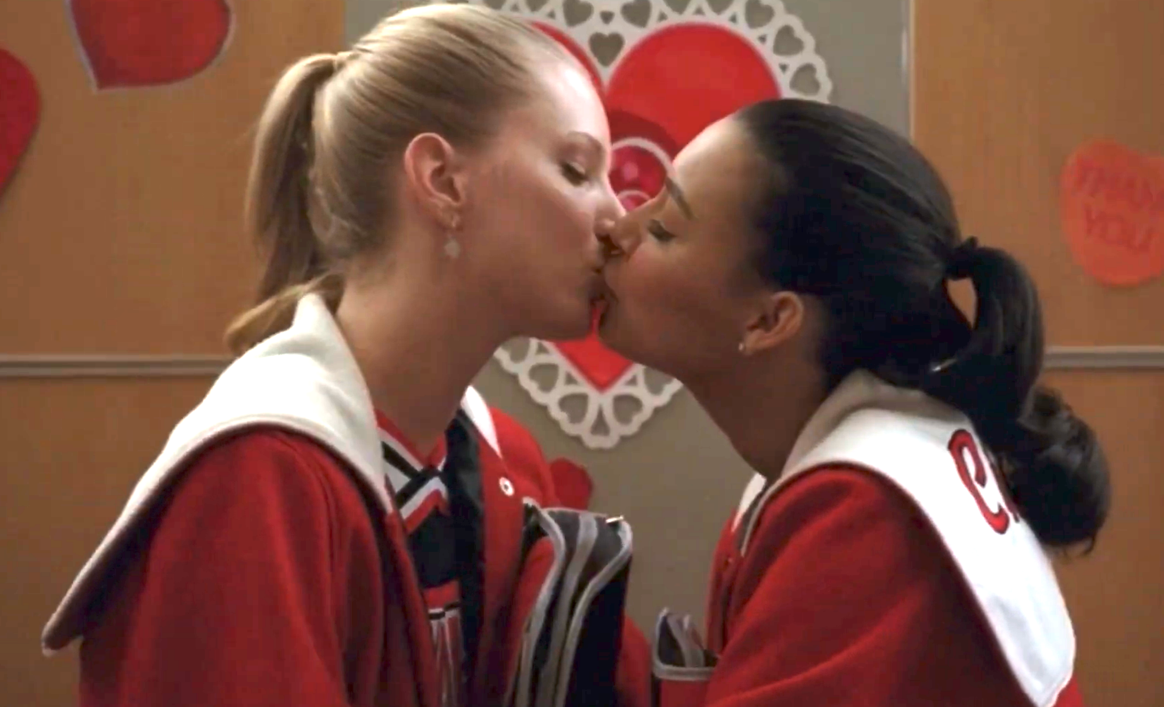 Two characters successful  cheerleading uniforms stock  a kiss, acceptable   against a backdrop with bosom  decorations, suggesting a melodramatic  oregon  romanticist  TV scene