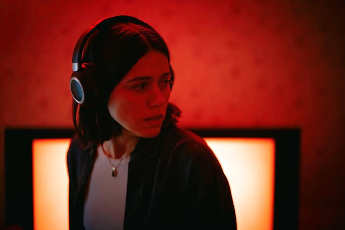 Person with headphones looks to the side, illuminated by a lukewarm  airy  from a surface  down  them