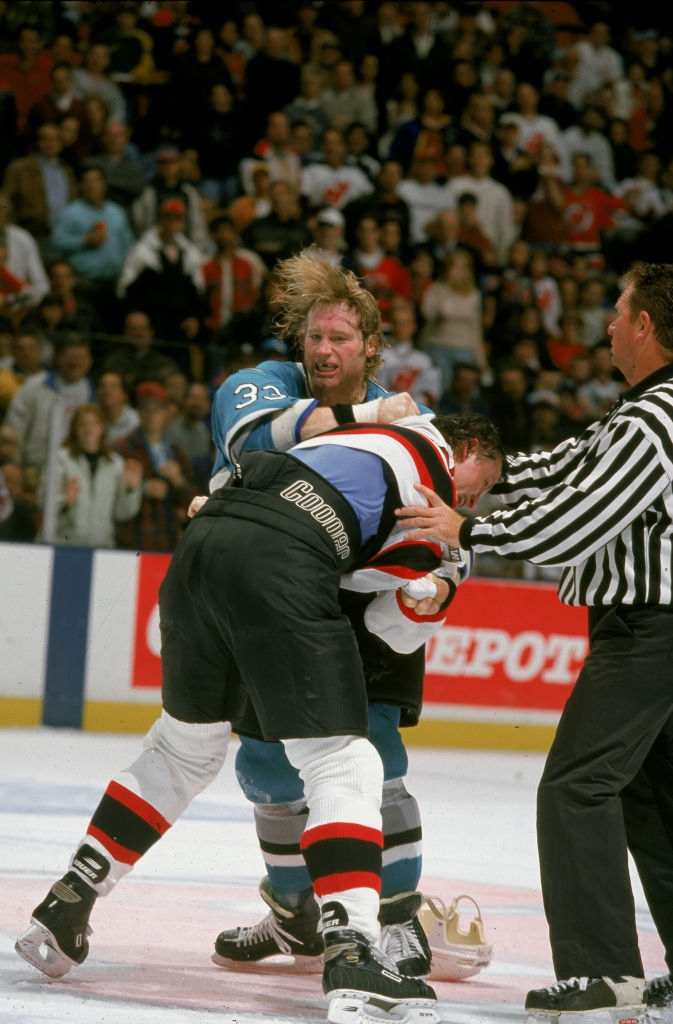 Hockey players are engaged successful  a combat  connected  the ice, with a referee attempting to abstracted  them during a game
