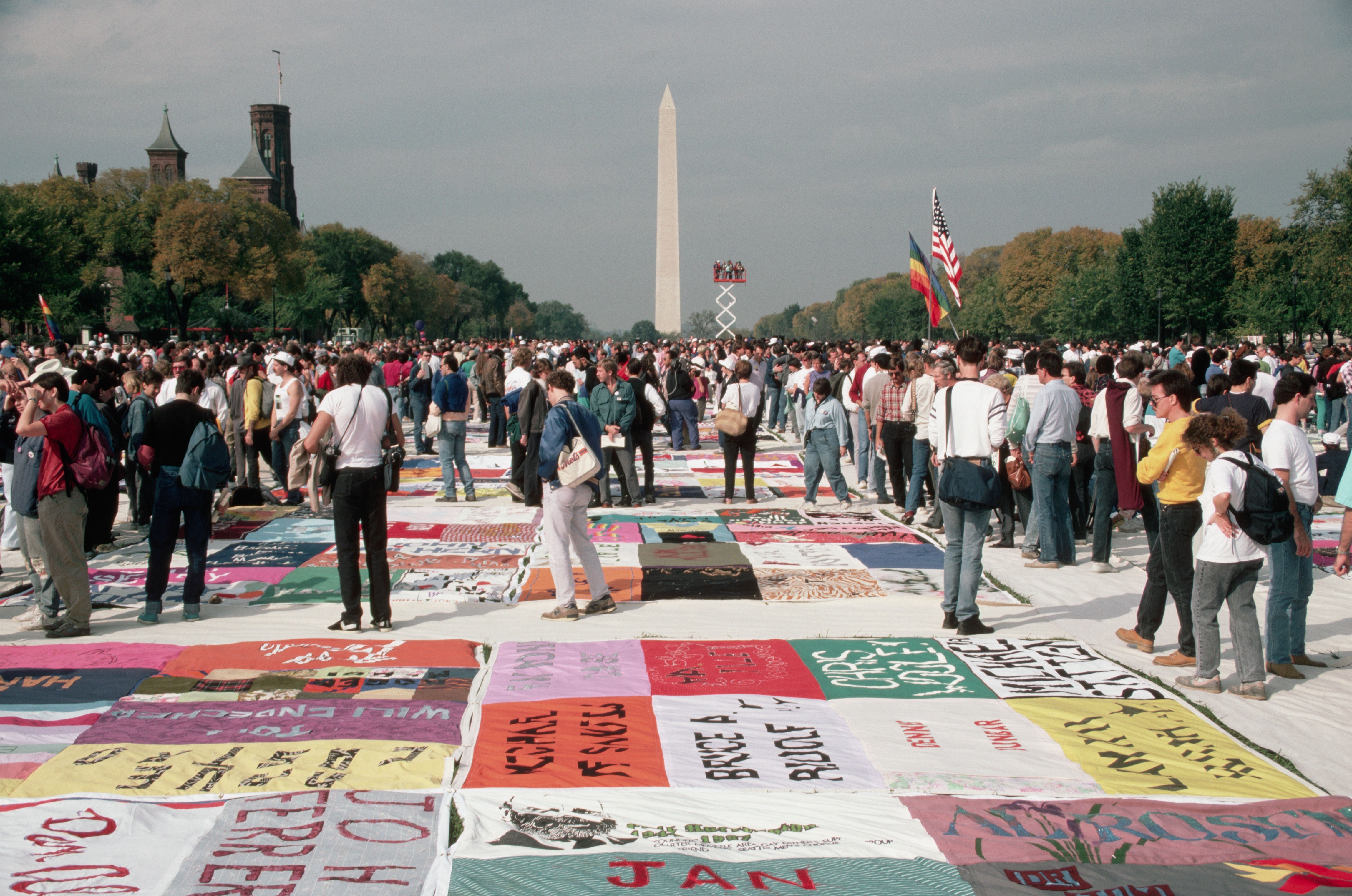 Large assemblage  gathered connected  National Mall with colorful AIDS Memorial Quilt sections displayed, Washington Monument successful  background