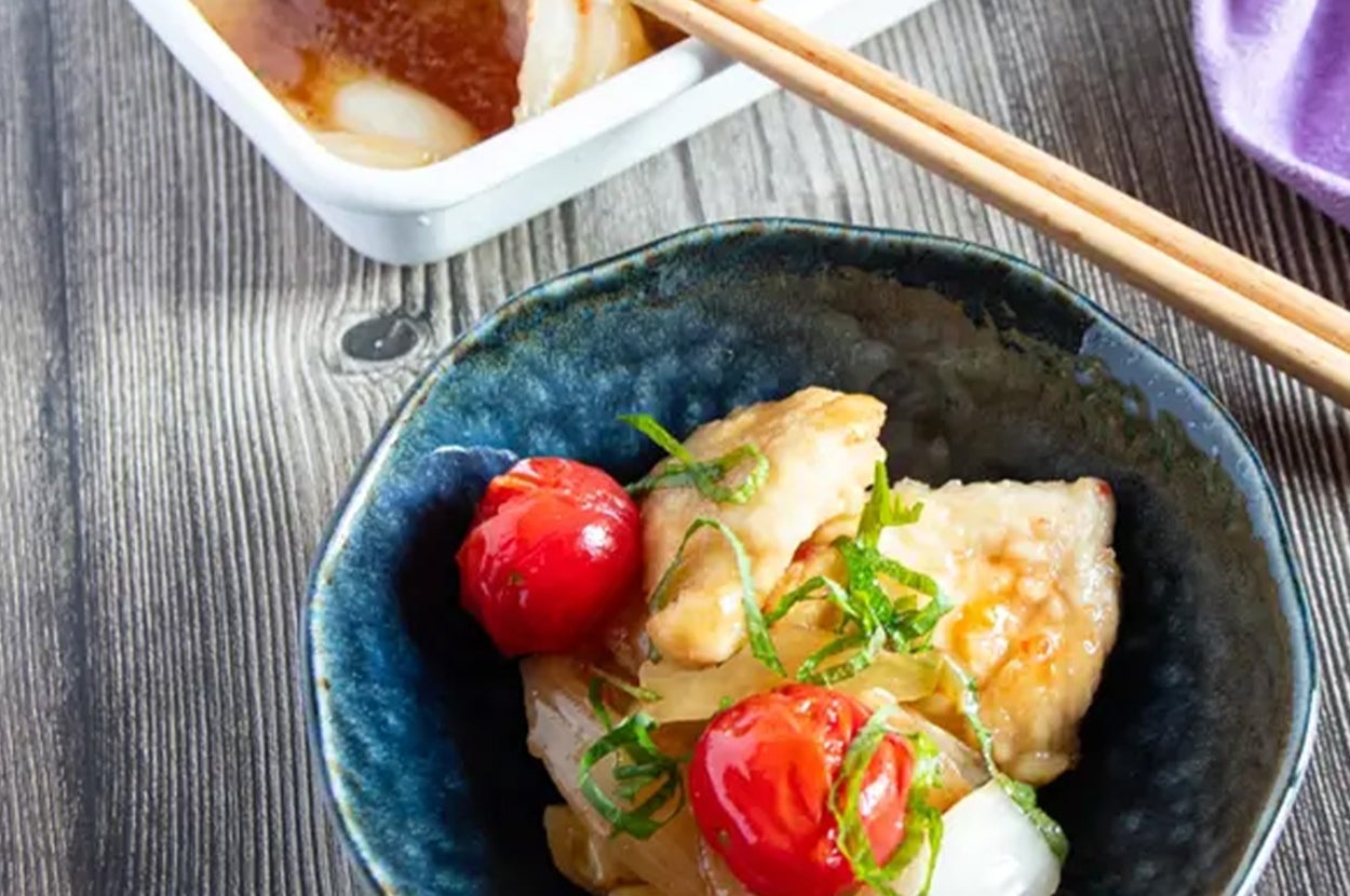 器に鶏肉、玉ねぎ、トマトが盛られた料理。上に大葉がのっている。