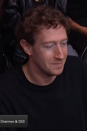 Mark Zuckerberg seated at a sports event, wearing a casual t shirt