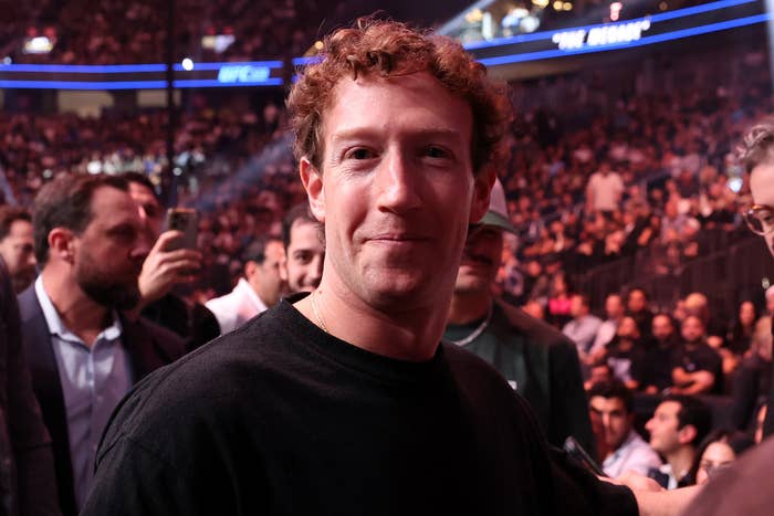 Mark Zuckerberg attending a crowded event, wearing a casual shirt, with a lively audience in the background