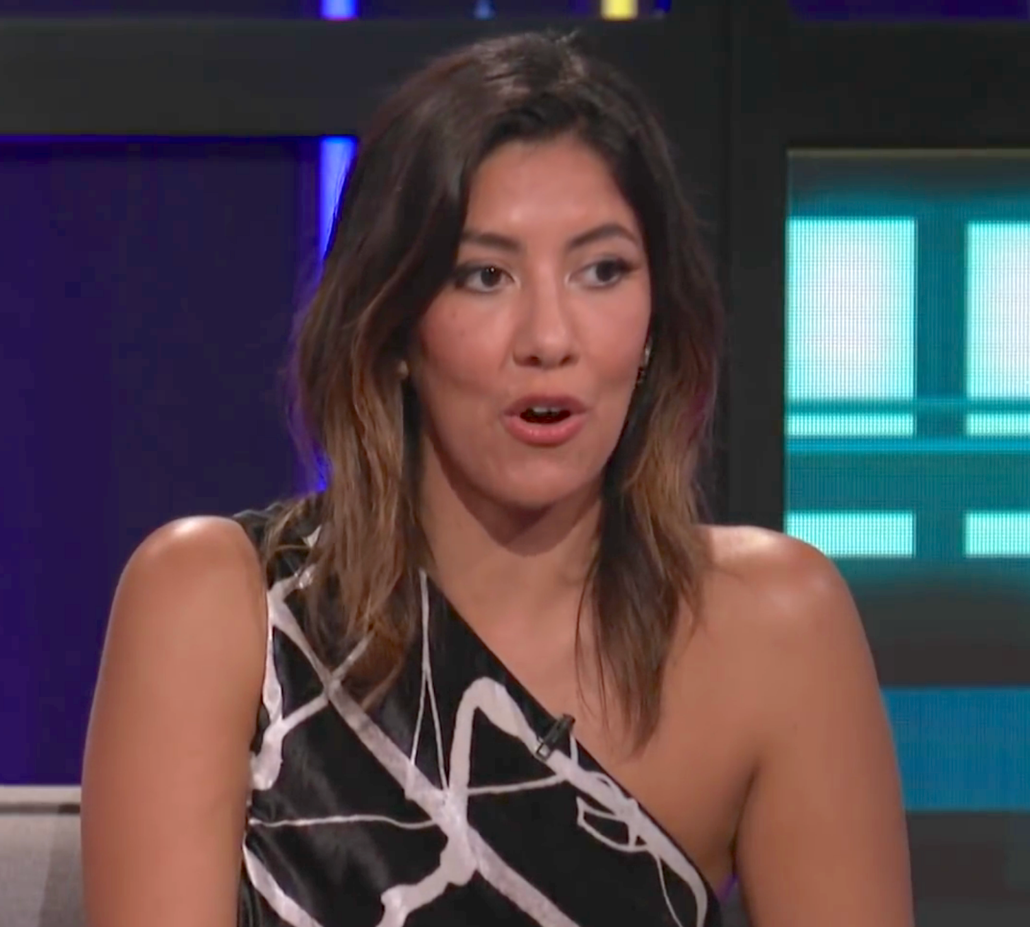 Person connected  a speech   amusement   wearing a stylish one-shoulder apical  with abstract patterns, speaking animatedly