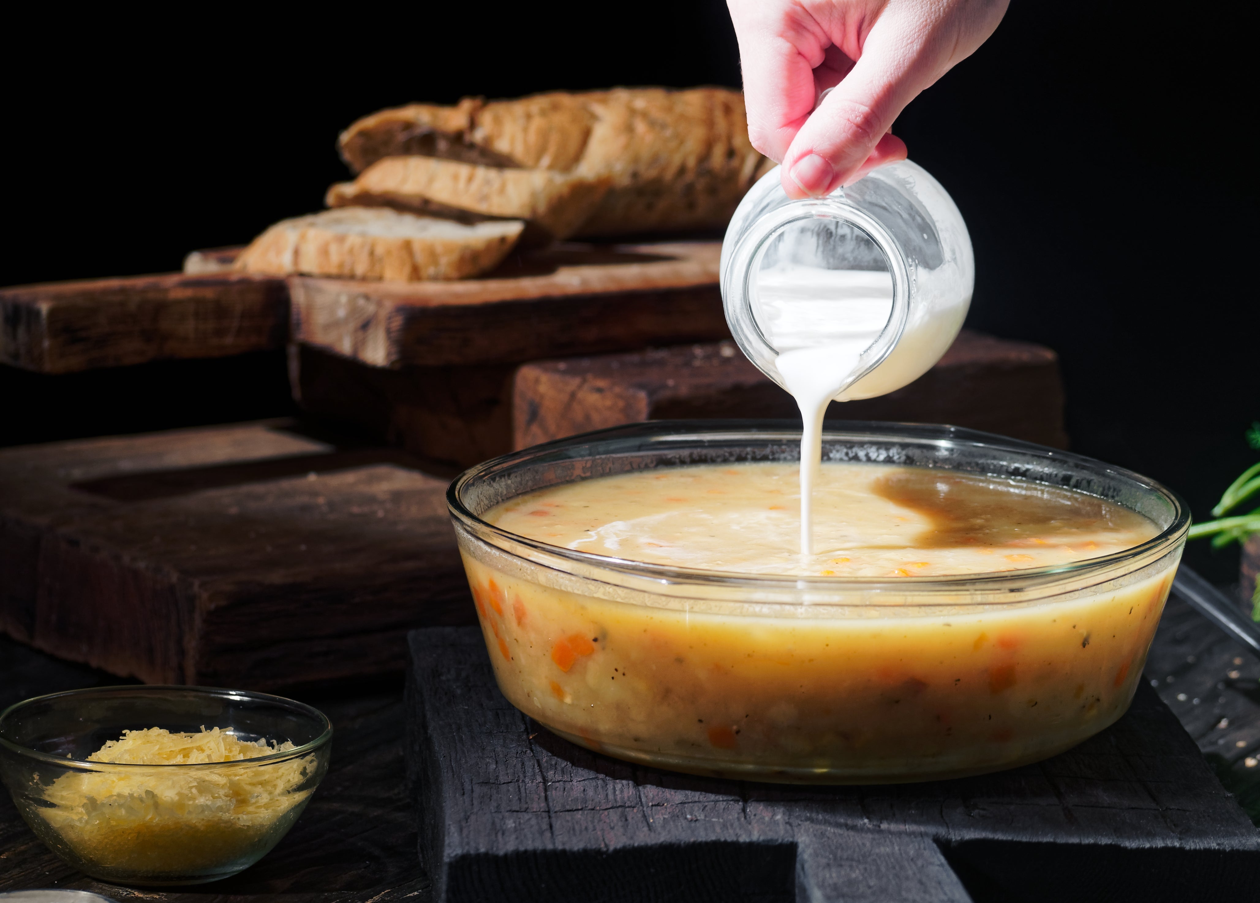 Hand pouring pick into a vessel of crockery connected a rustic array with breadstuff successful the background, emphasizing a homemade, comforting setting