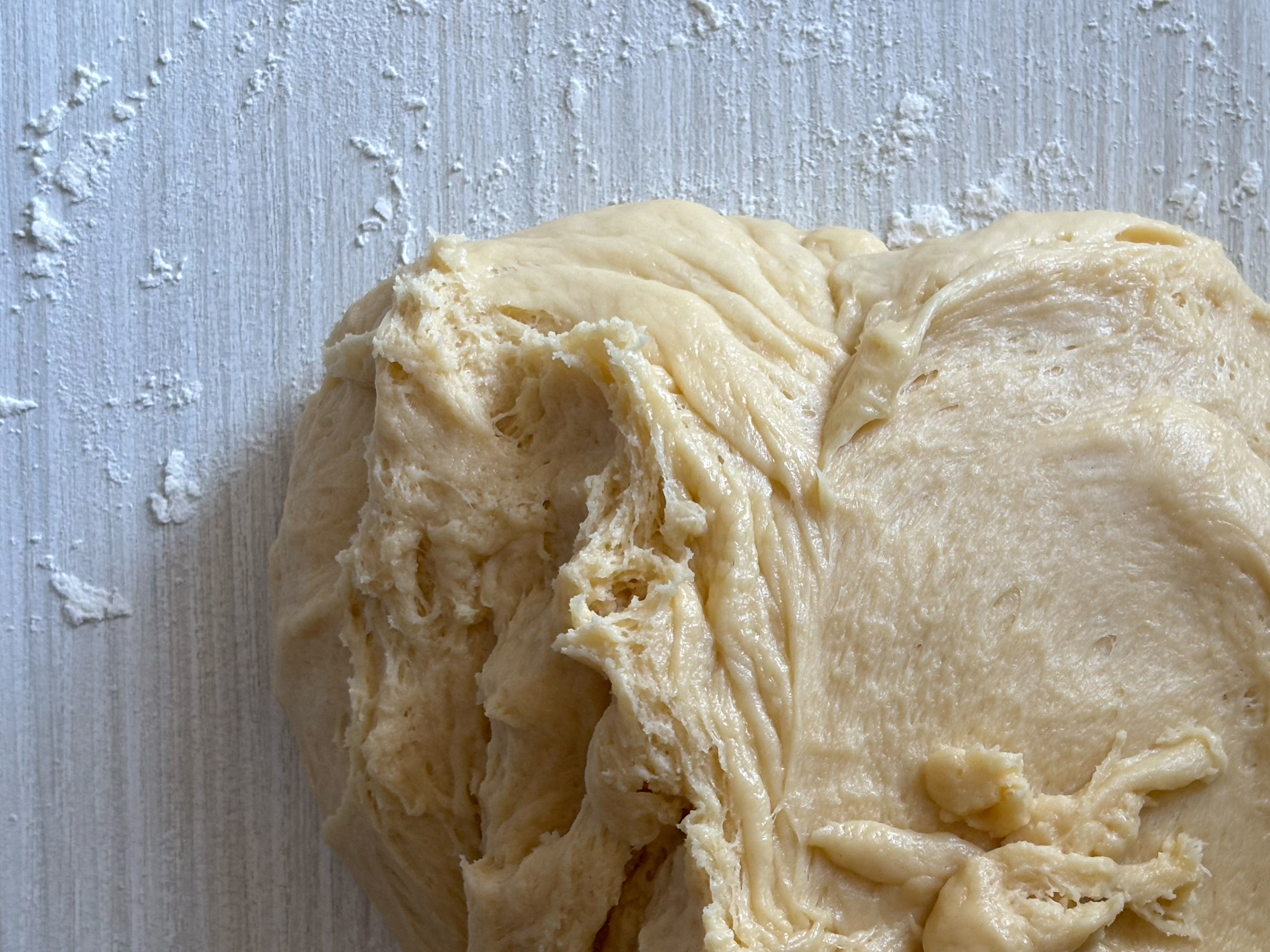 Close-up of earthy   breadstuff  dough connected  a floured surface, highlighting its texture and folds