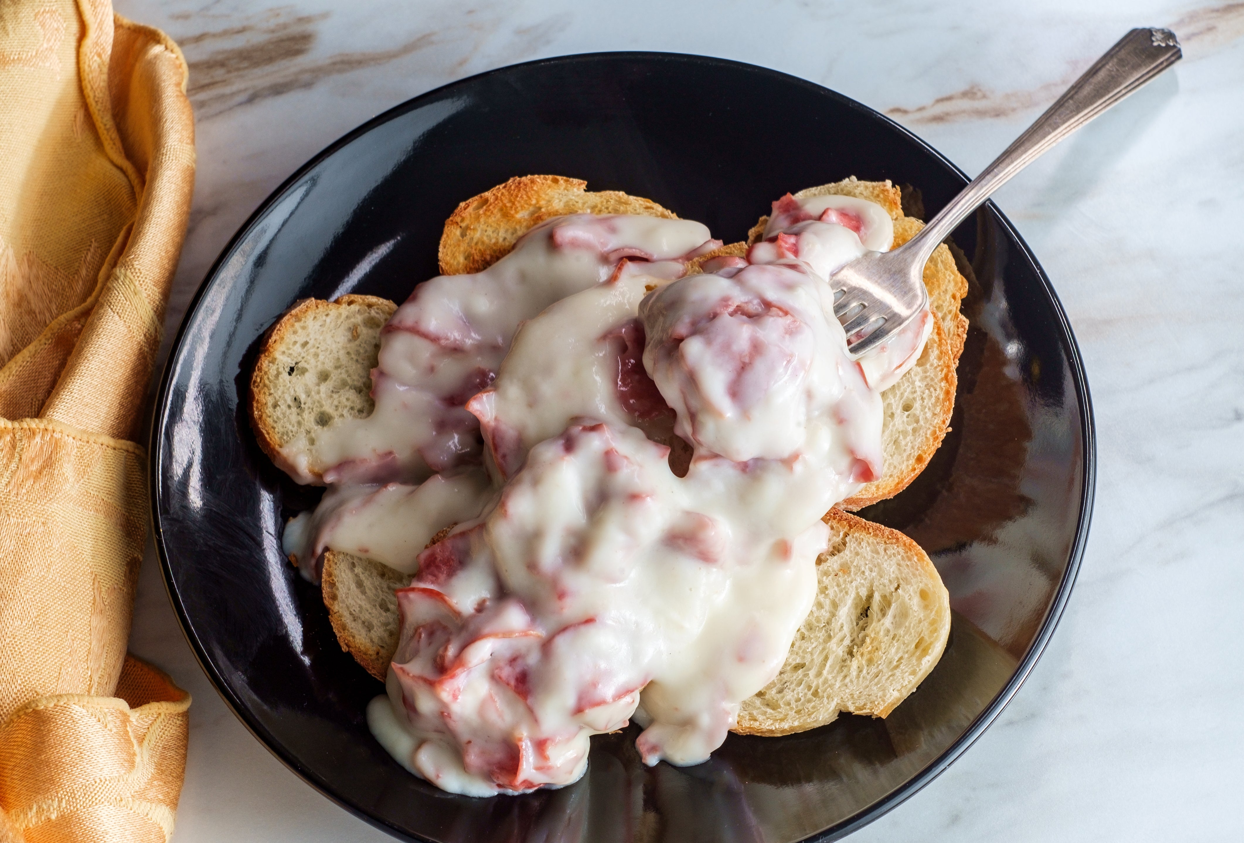 Open-faced sandwich with meatballs and melted food connected sliced bread, served connected a achromatic sheet with a fork
