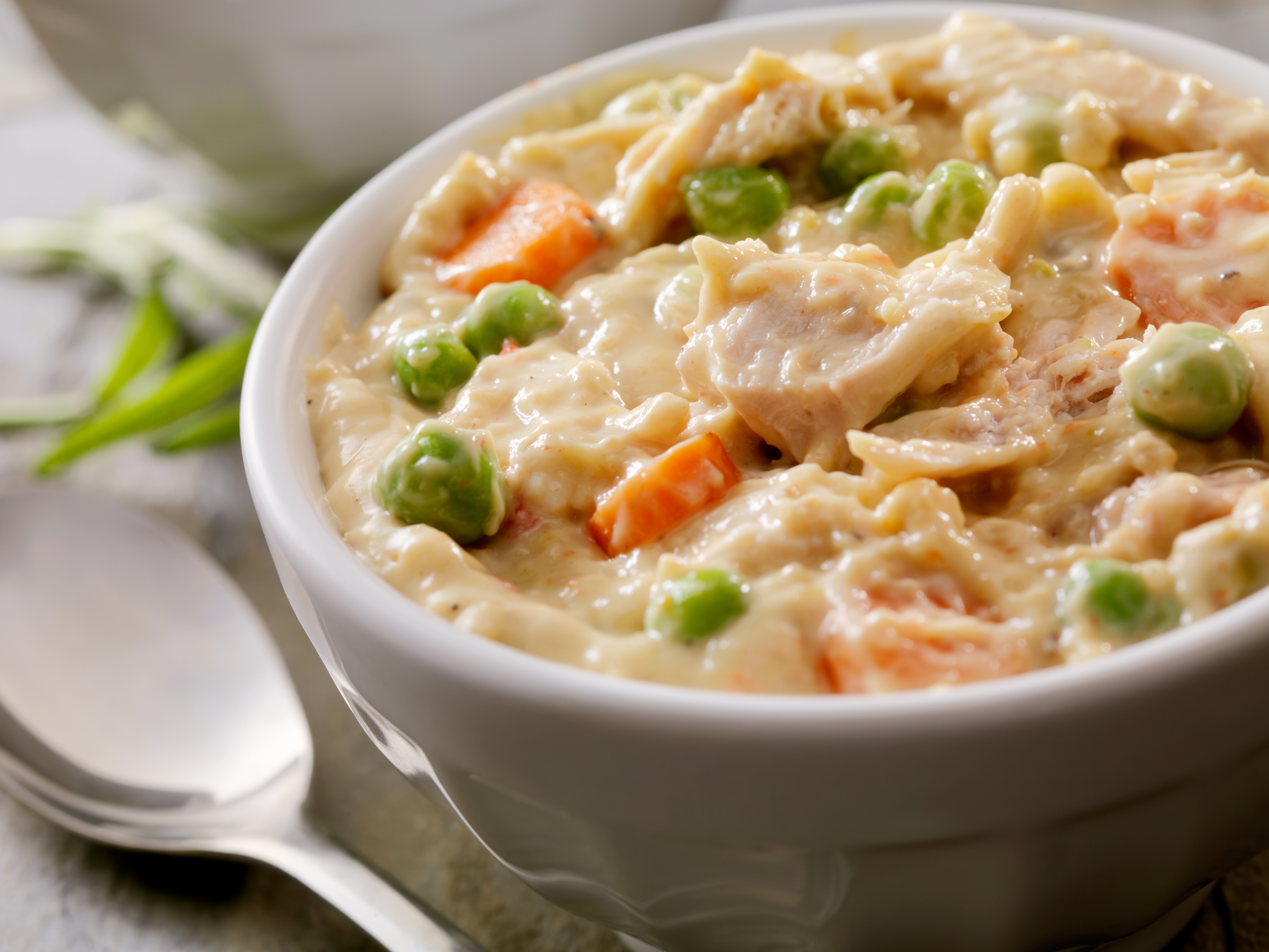 Close-up of a vessel of creamy chickenhearted cookware pastry filling with chunks of chicken, peas, and carrots