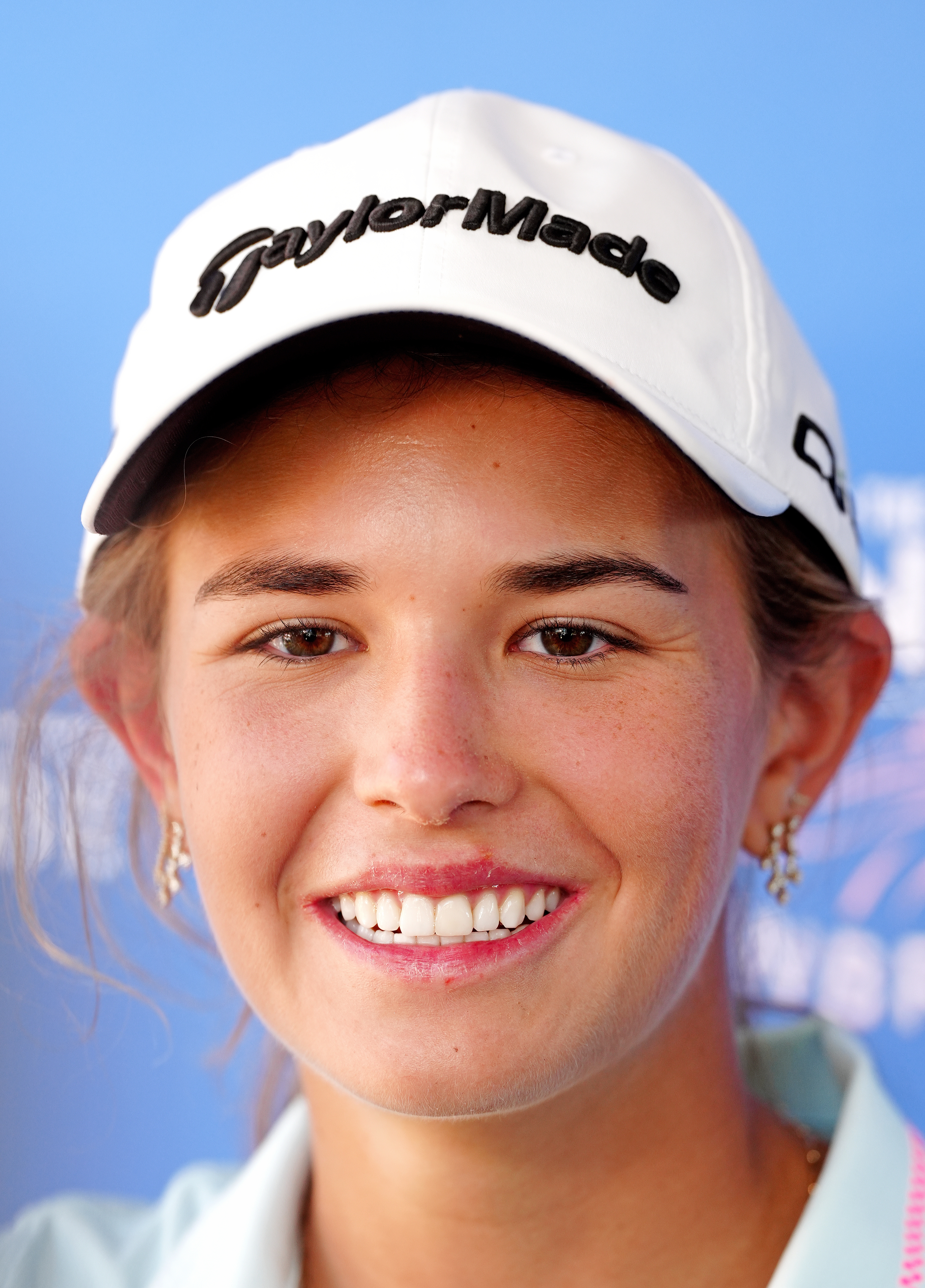Person wearing a branded cap, smiling astatine  the camera. Simple, casual benignant   with earrings, featured successful  a personage  article