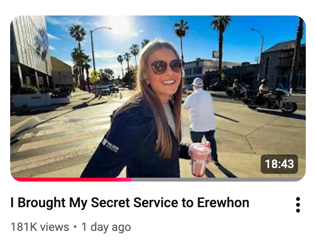 Smiling pistillate   with agelong  hairsbreadth  holds a portion  portion    walking connected  a sunny municipality  thoroughfare  with disposable   thenar  trees and pedestrians