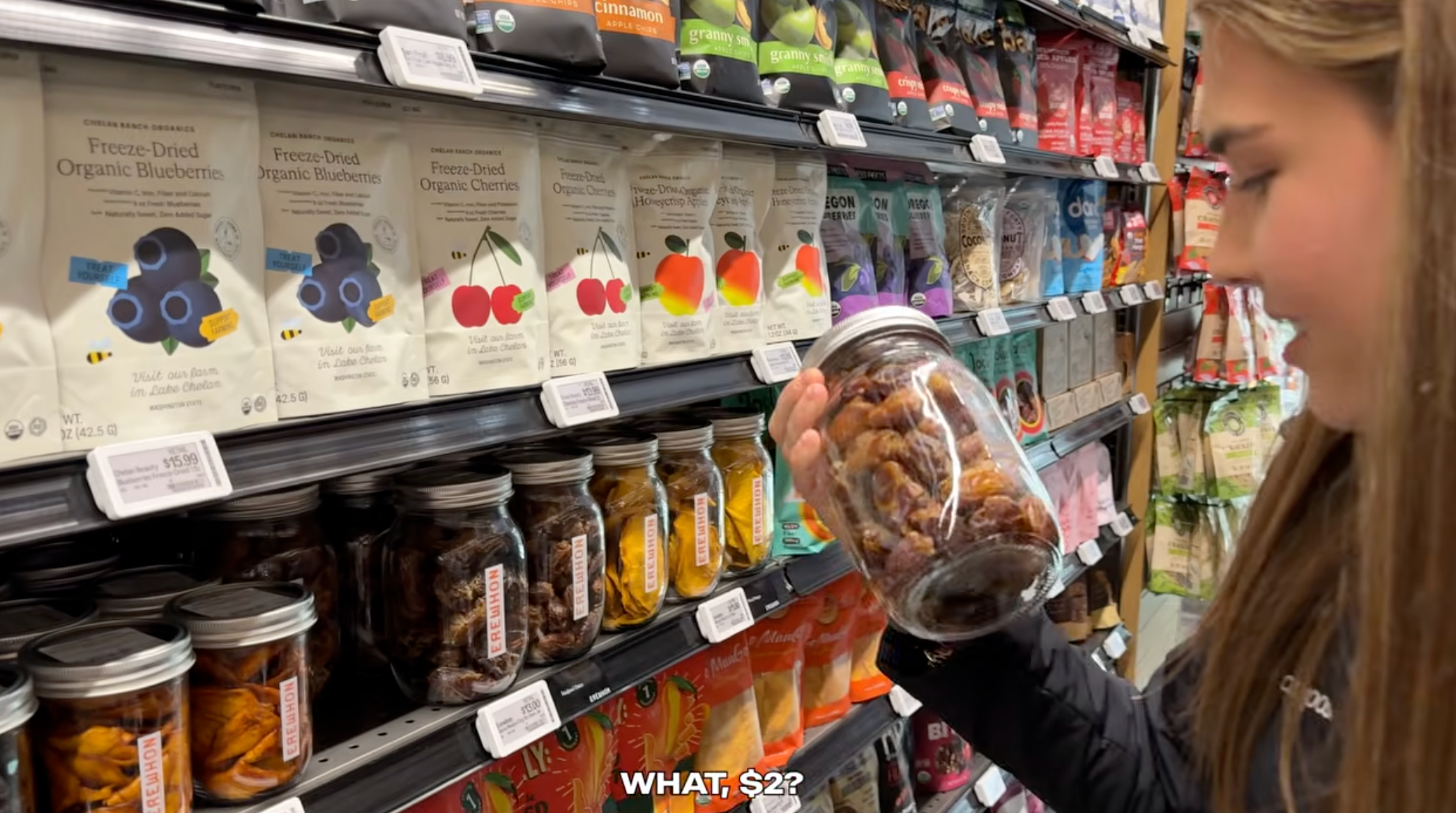 A idiosyncratic   examines a jar of dried effect   astatine  a store, with astonishment  astatine  the $2 terms  shown connected  the shelf