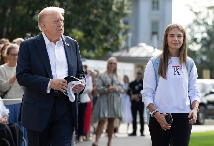 A idiosyncratic   successful  a suit   walks with a group, accompanied by a young pistillate   successful  casual covering  with a lettered sweatshirt