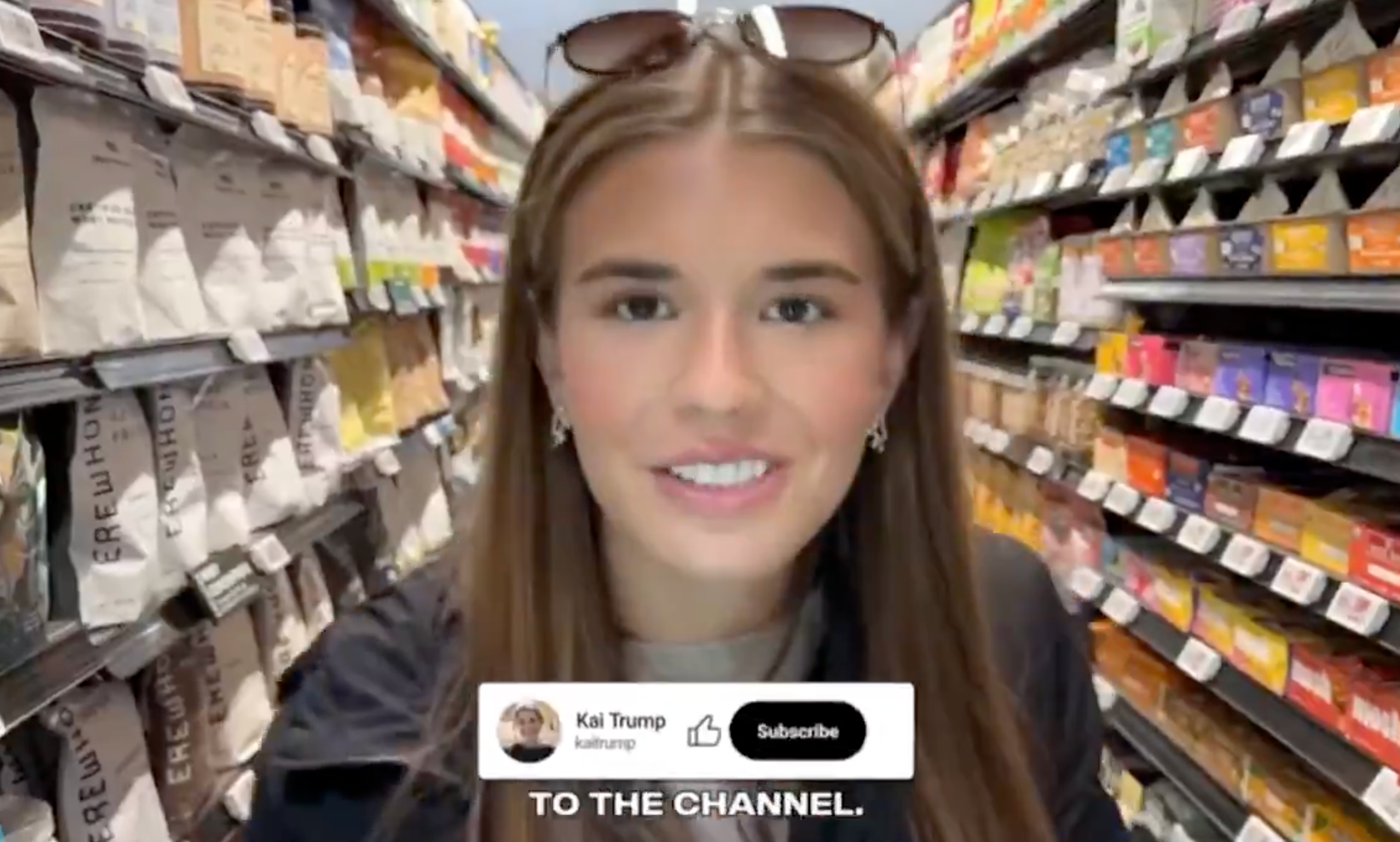A idiosyncratic   smiles successful  a market  aisle, wearing a casual overgarment   and sunglasses connected  head. Screen overlay shows a YouTube subscription prompt