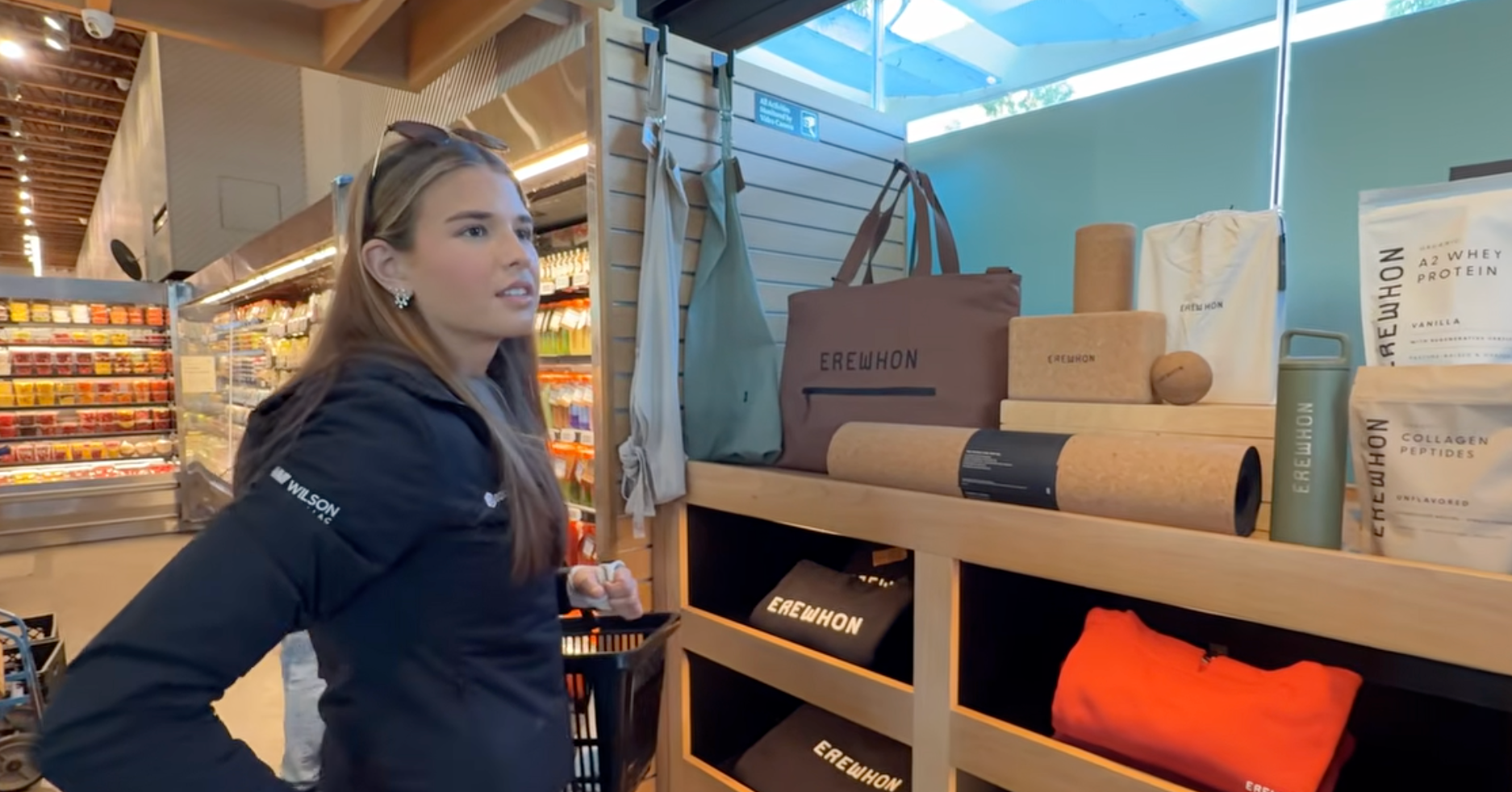 A idiosyncratic   successful  a store   looks astatine  shelves displaying Erewhon branded bags, yoga mats, and bottles. The mounting  appears organized and modern