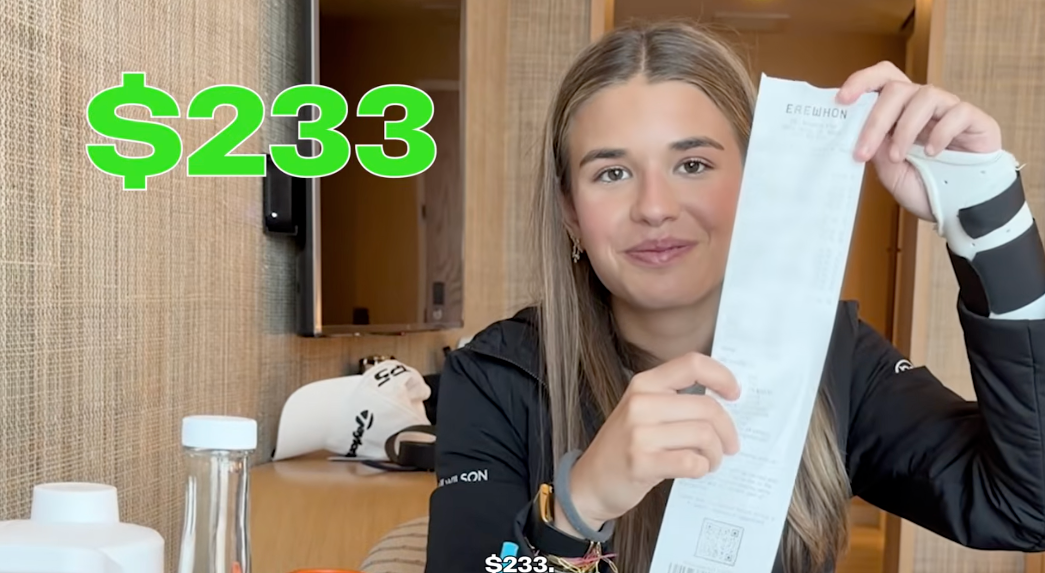 Person holding a agelong  receipt and smiling, with "$233" successful  agleam  substance   above. Wearing a casual, achromatic  long-sleeve top