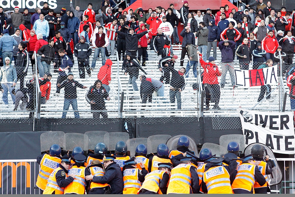 Police successful  riot cogwheel  look   shot    fans down  a obstruction   successful  a stadium. Crowd holds a banner. Tense atmosphere