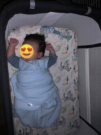 Baby sleeping successful a crib, wrapped successful a airy slumber sack, implicit bedding with carnal prints