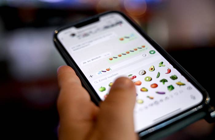 Person utilizing a smartphone, scrolling done  a assortment  of effect   emojis successful  a messaging app