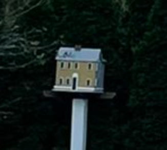 Model of a tiny  two-story location   with a achromatic  basal  and acheronian  roof, mounted connected  a rod  successful  beforehand   of trees